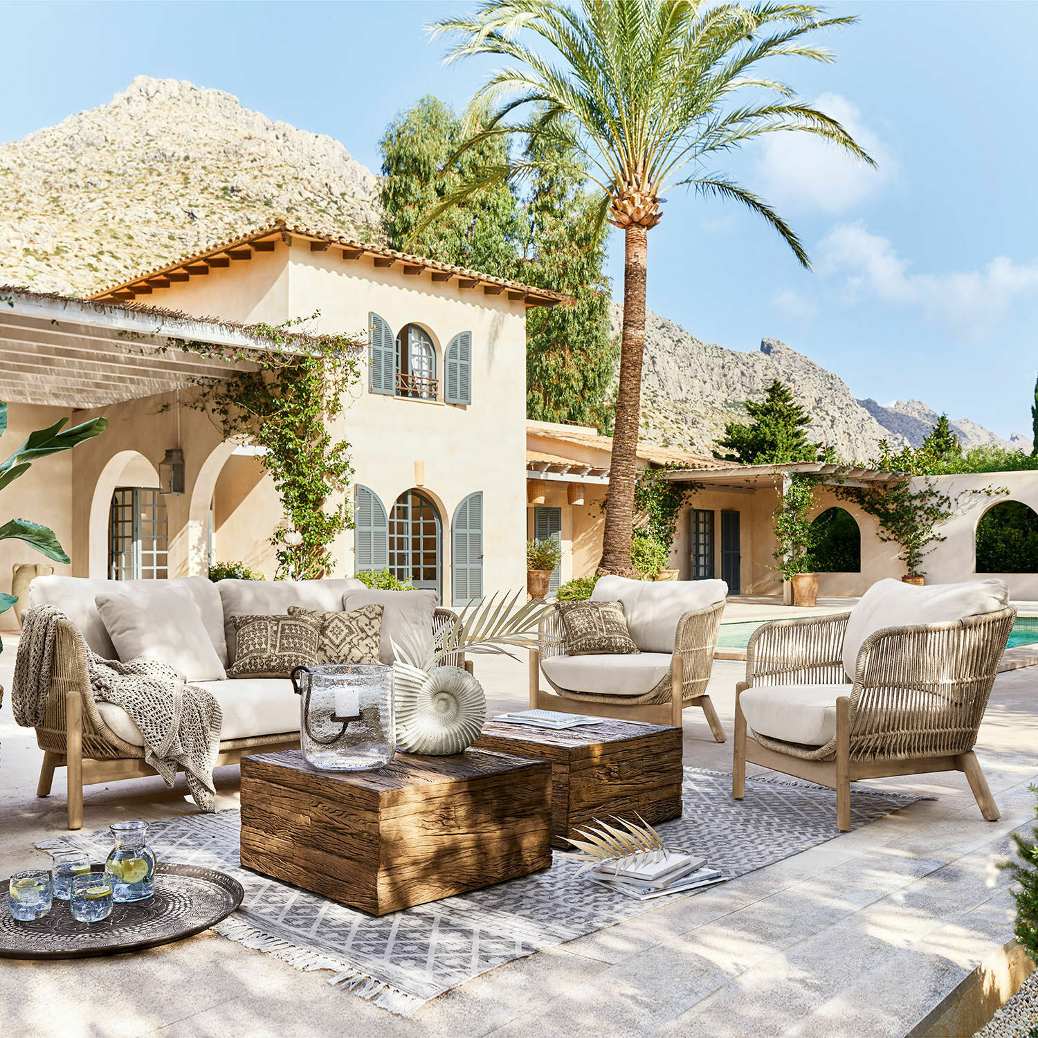 Tuinset FSC®-100% Belvidere Buitenmeubelset met beige kussens en houten tafel op terras bij zwembad in mediterrane stijl