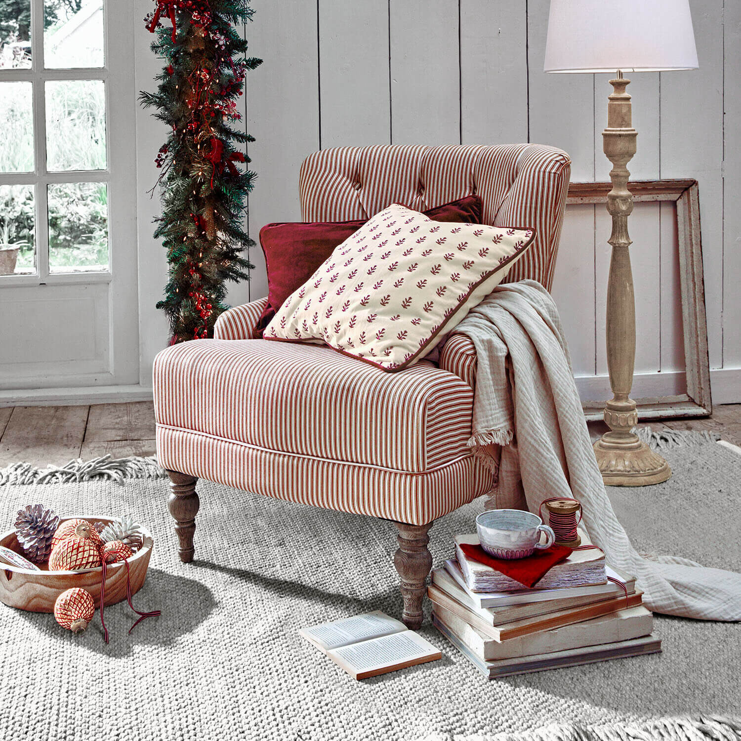 Fauteuil Amuran Gestreepte stoel van rood-witte stof met kussens en lamp in een gezellige kamer