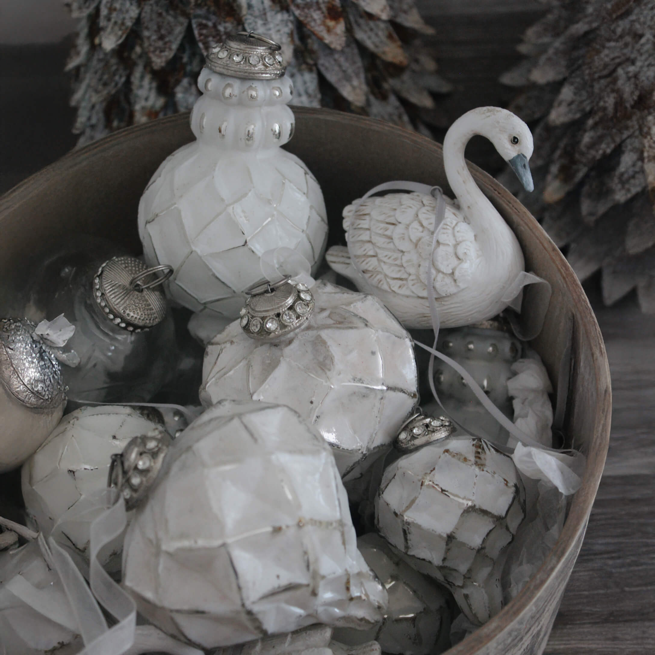 Witte kerstversieringen van keramiek en glas in een houten schaal, winterse ornamenten