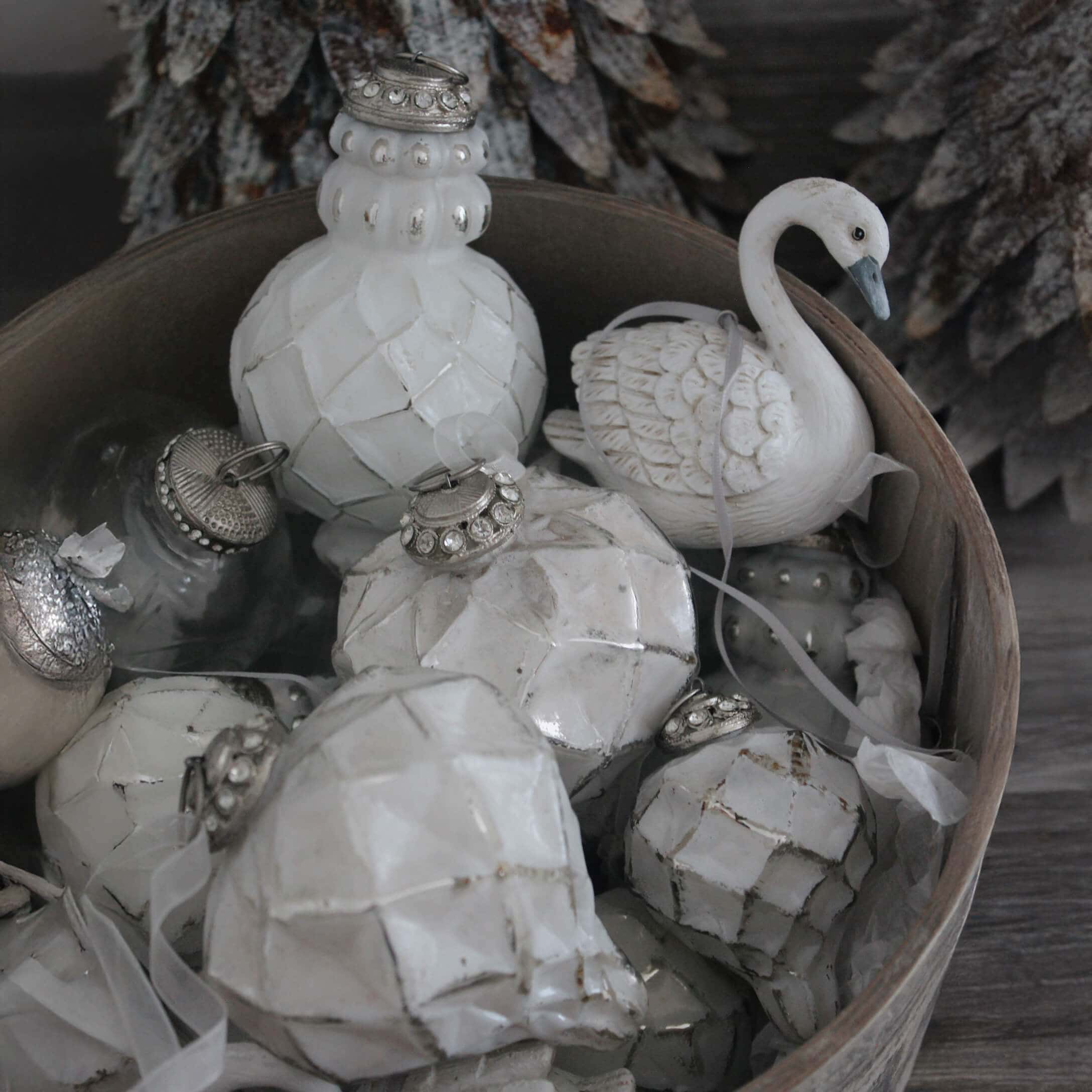 Witte kerstversieringen van keramiek en glas in een houten schaal, winterse ornamenten