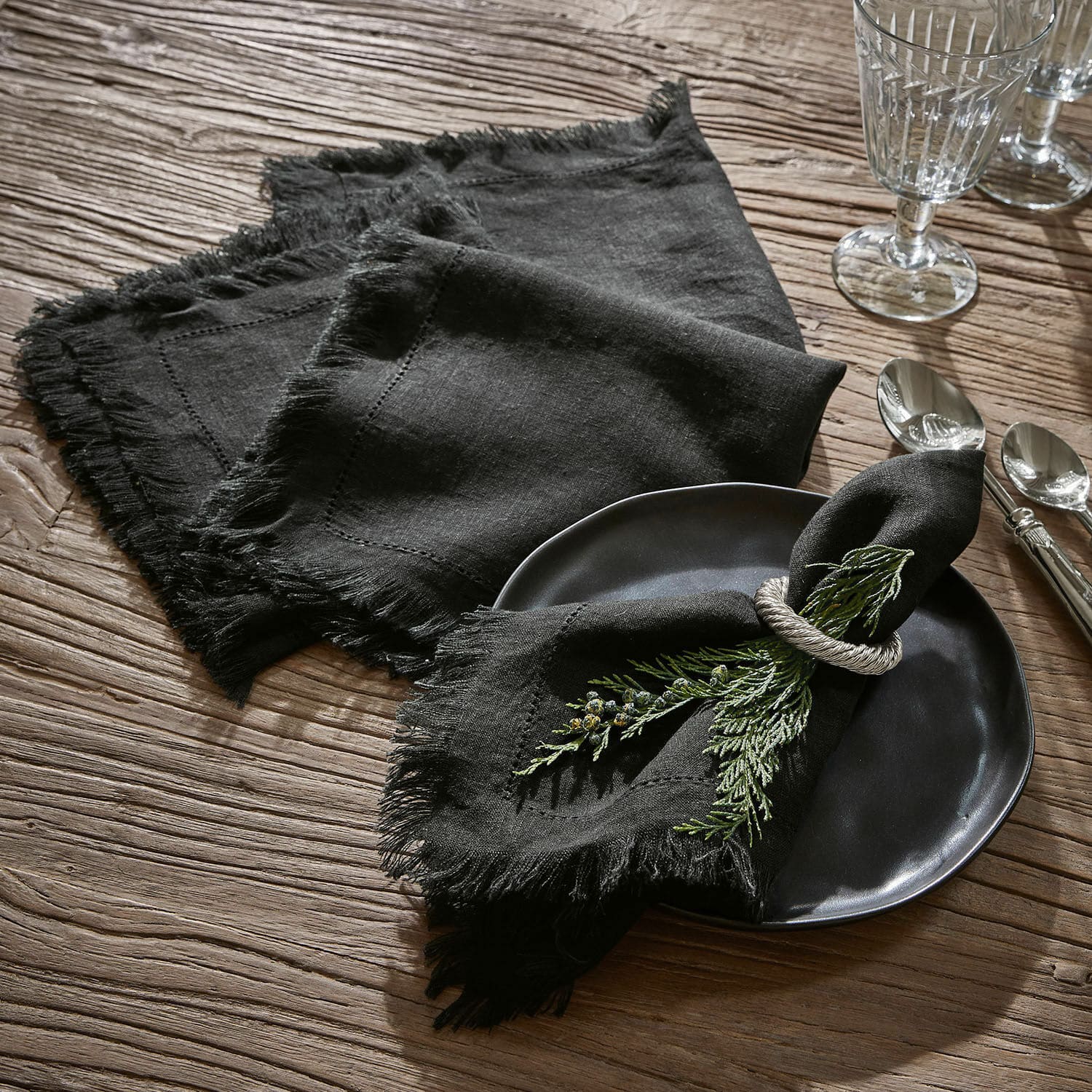 Servet set van 4 Pibrac Zwarte linnen servetten met franjes op houten tafel met groene takjes als decoratie