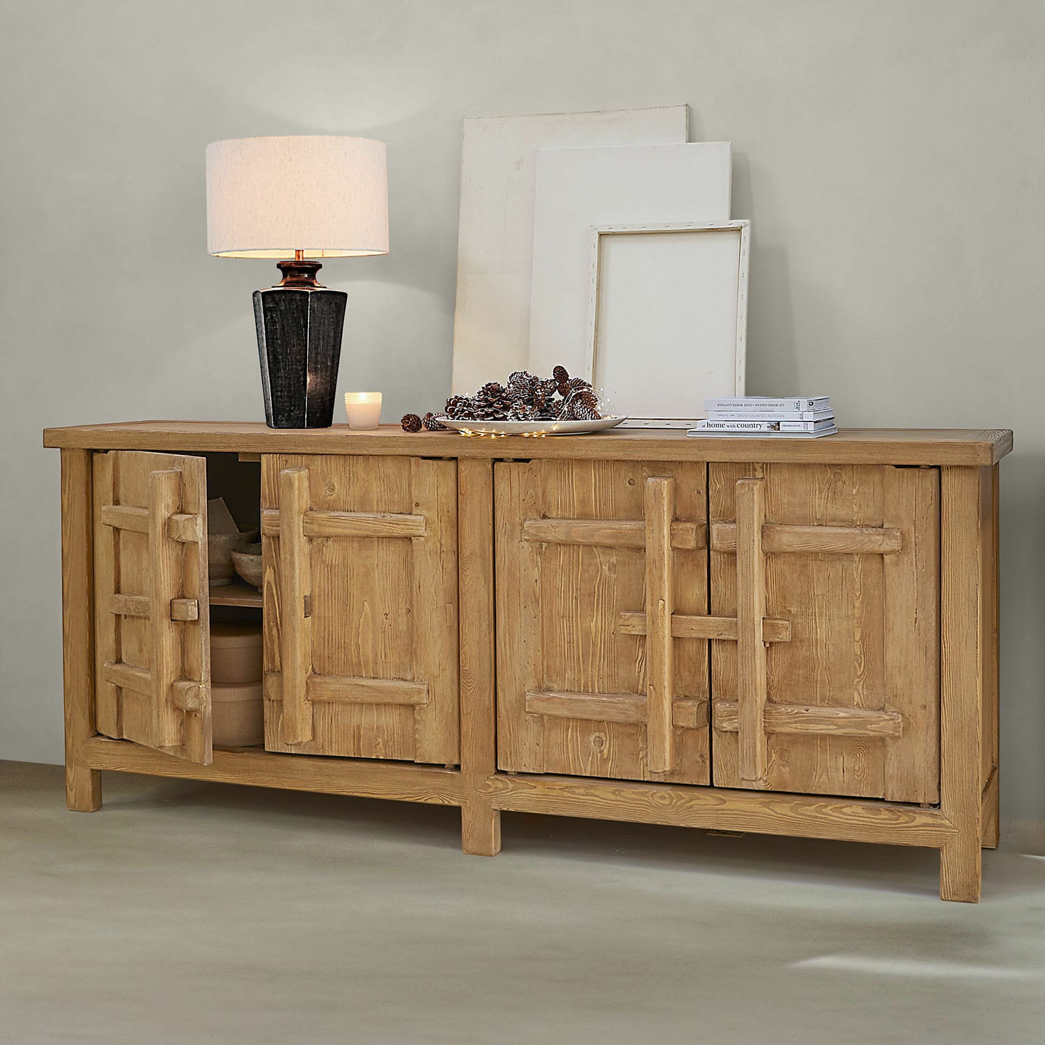 Dressoir van natuurlijk hout met vier deuren, lamp en decoraties op het blad in een moderne ruimte