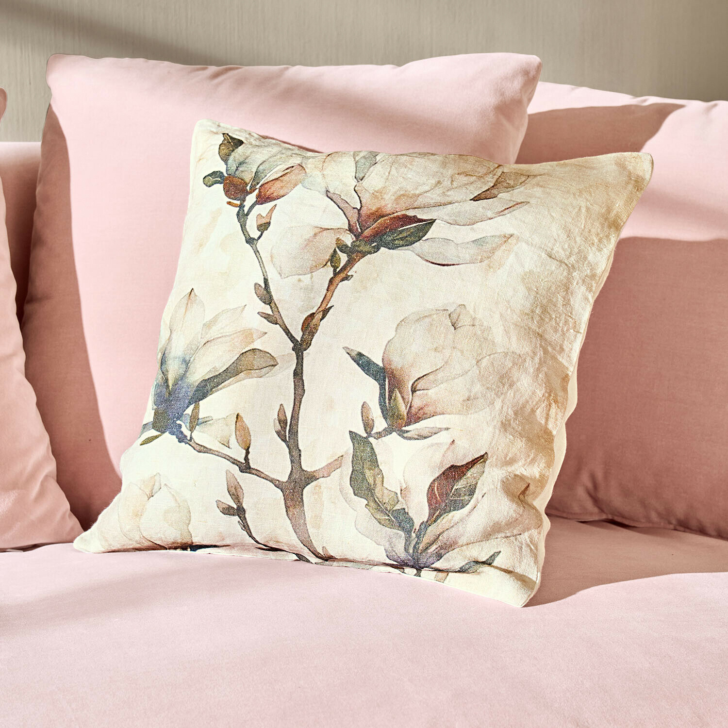 Linnen sierkussen met bloemenprint op roze bank, zachte en stijlvolle woondecoratie