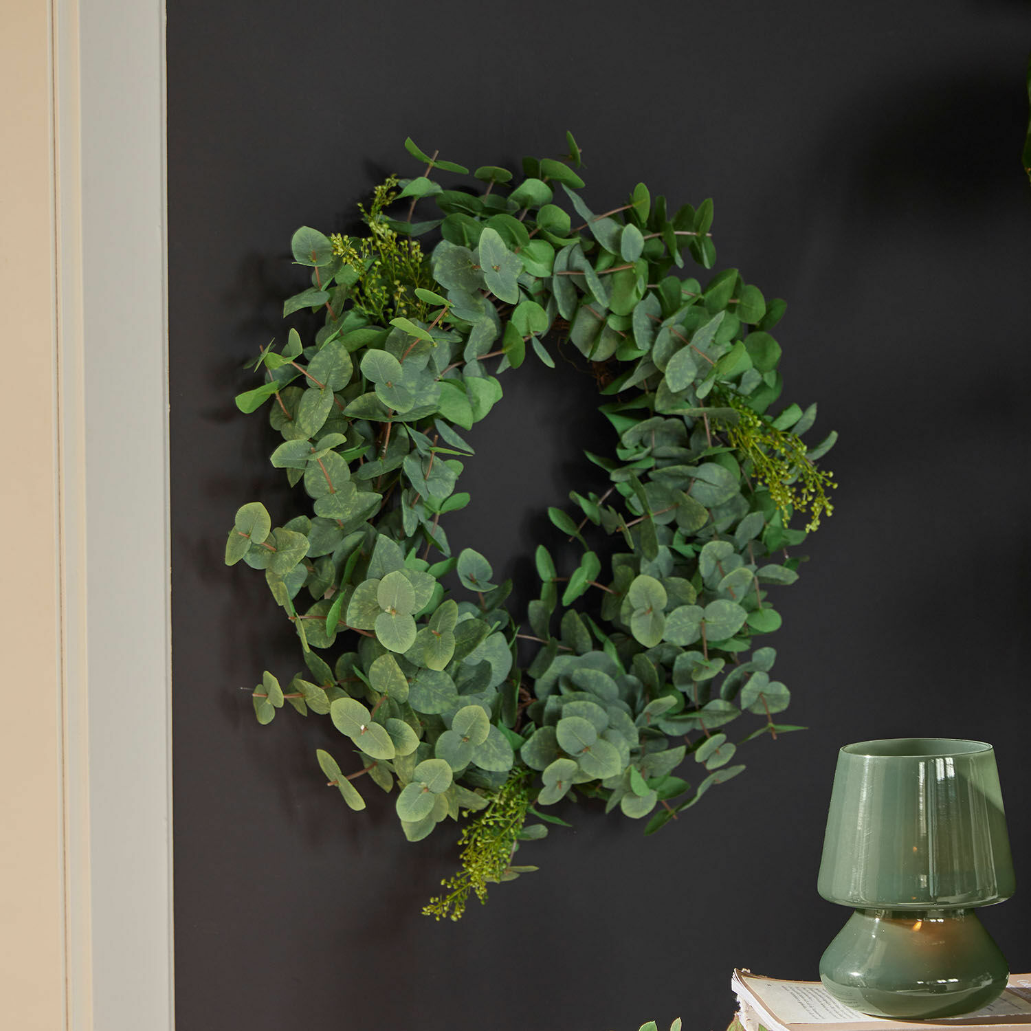 Decoratieve krans van groene eucalyptusbladeren aan donkere muur voor interieurdecoratie
