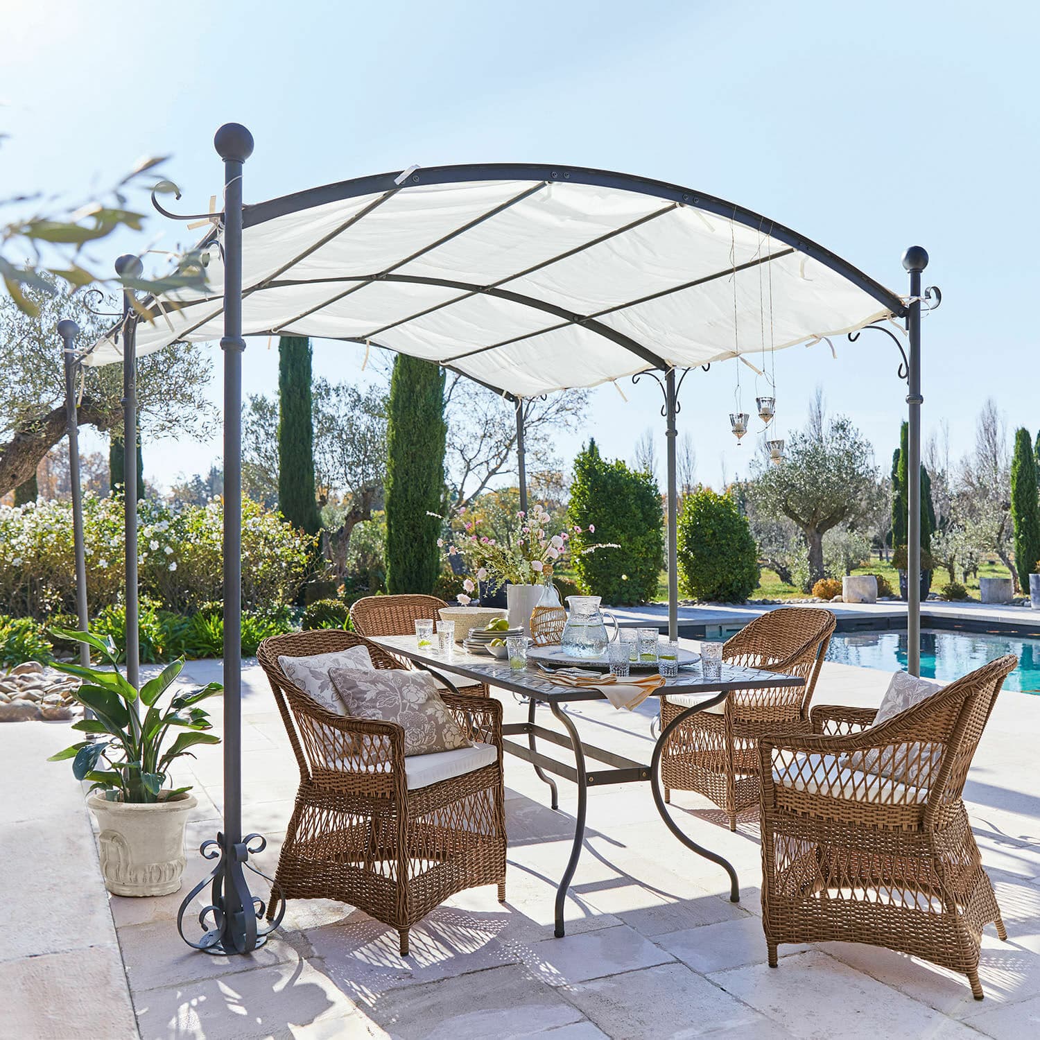 Pergola Yarl Tuinmeubelset van bruin rattan onder een wit metalen paviljoen bij het zwembad