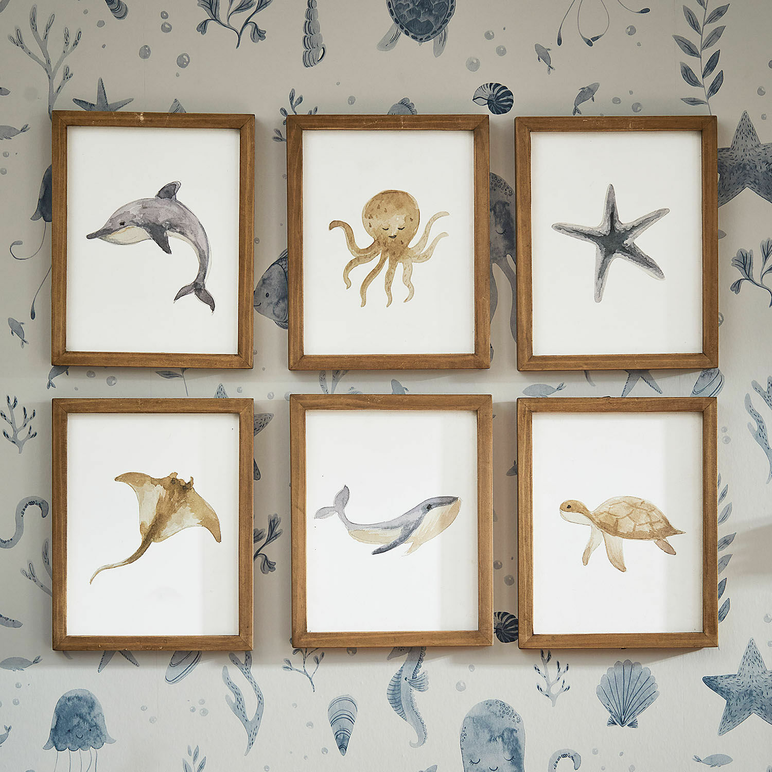 Fotoset van 6 Nibblu Set van zes houten lijsten met aquarel schilderijen van zeedieren aan muur met oceaandessin