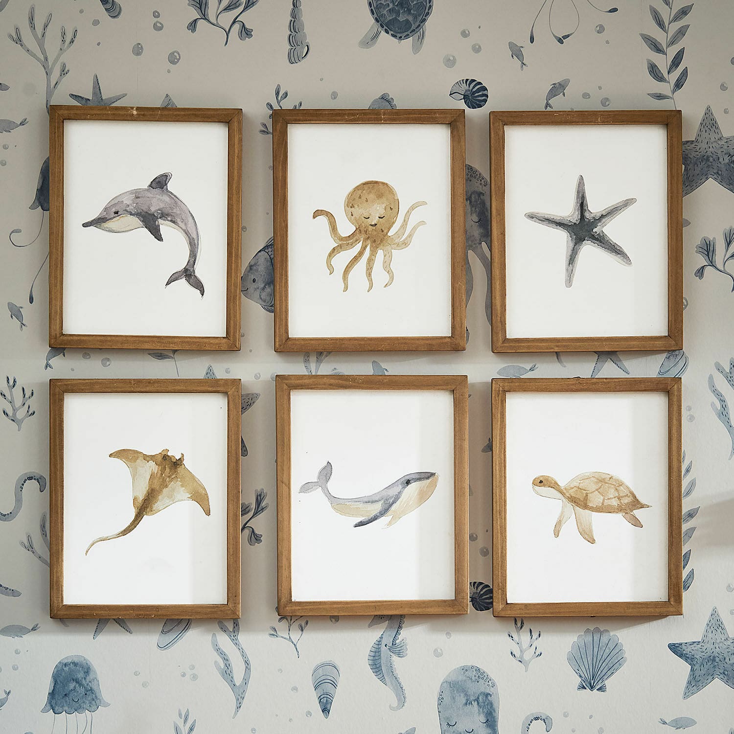 Fotoset van 6 Nibblu Set van zes houten lijsten met aquarel schilderijen van zeedieren aan muur met oceaandessin