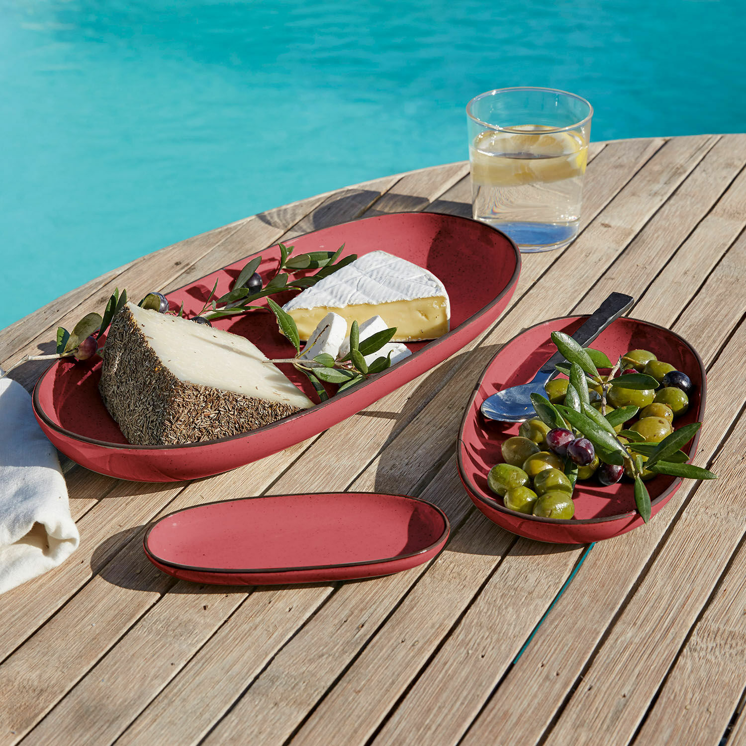 Serveerschaal set van 3 Biarré Rode ovale keramische borden met kaas en olijven op houten tafel bij het zwembad