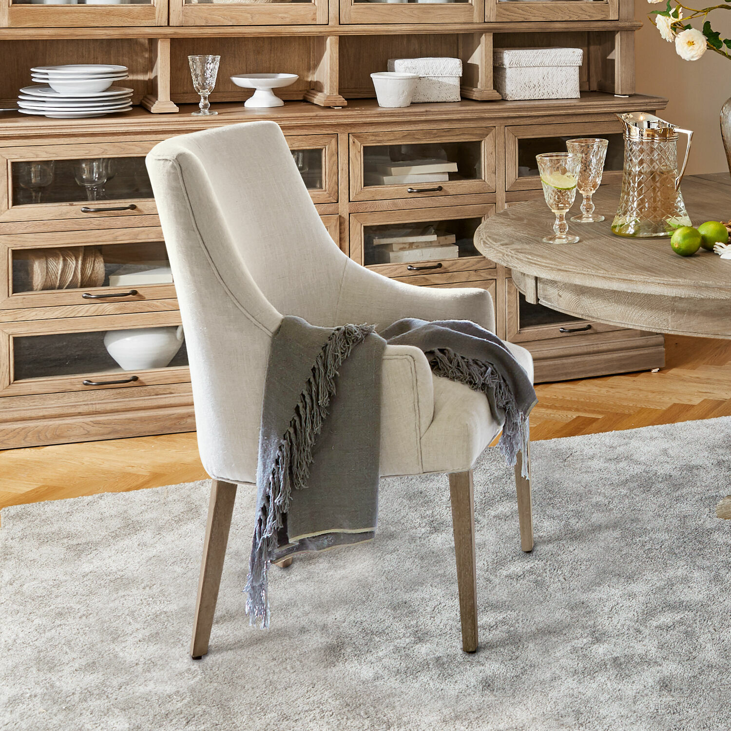 Stoel Hyeres Beige gestoffeerde stoel met houten poten en grijze deken in gezellige woonkamer met houten kast