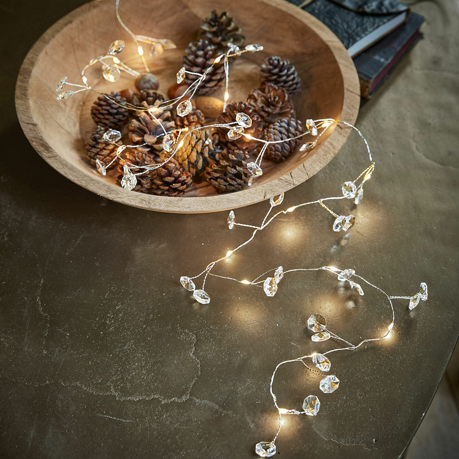 Ledlichtsnoer Laurits Houten schaal met dennenappels en fijne lichtsnoer met kristallen versiering op tafel