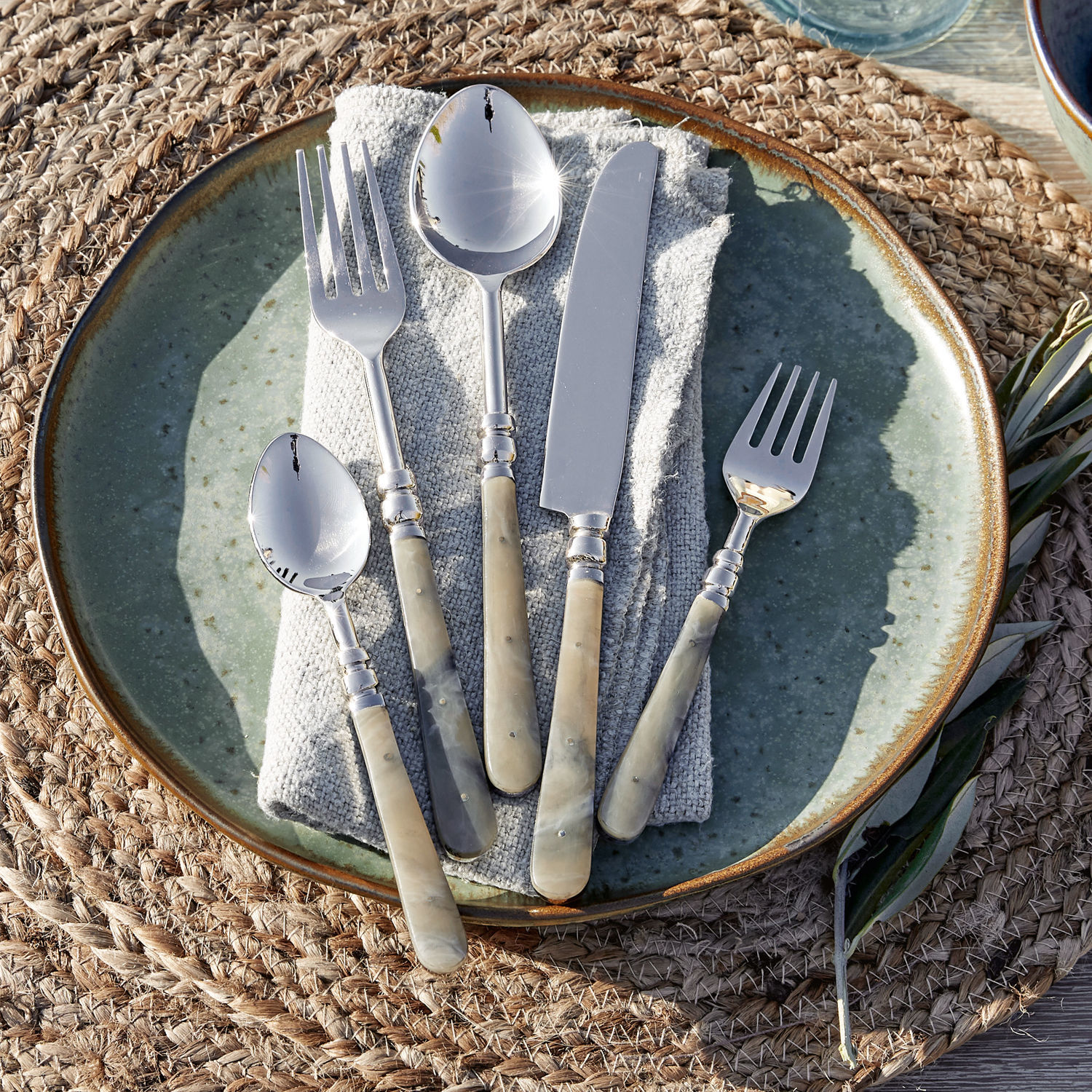 Bestekset met beige parelmoeren handvatten op groene bord, stijlvolle tafeldecoratie