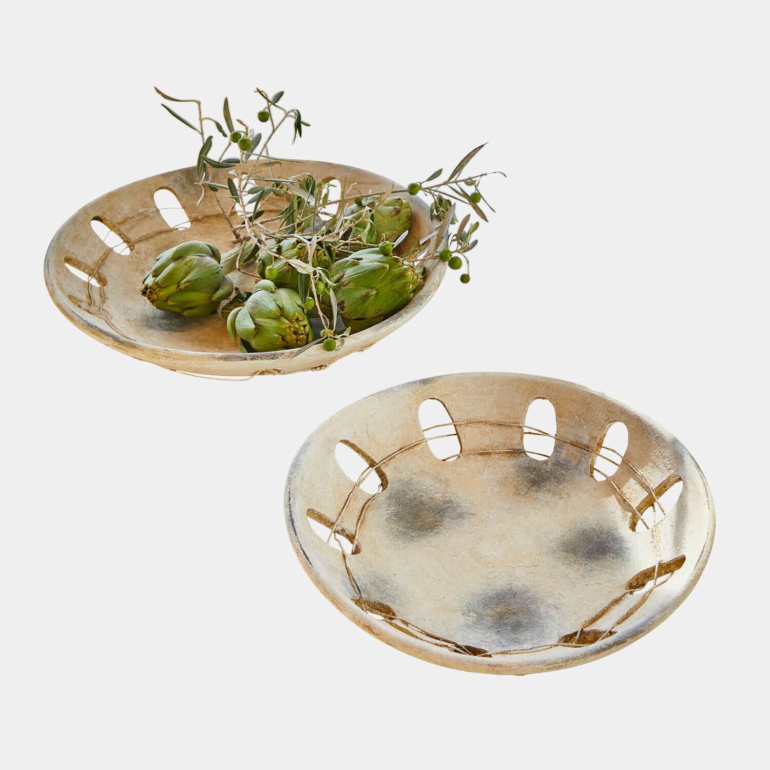 Twee decoratieve beige keramische kommen met openingen, één gevuld met groene artisjokken
