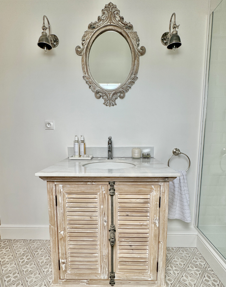 Badkamer met vintage houten onderkast en decoratieve wandspiegel boven de wastafel
