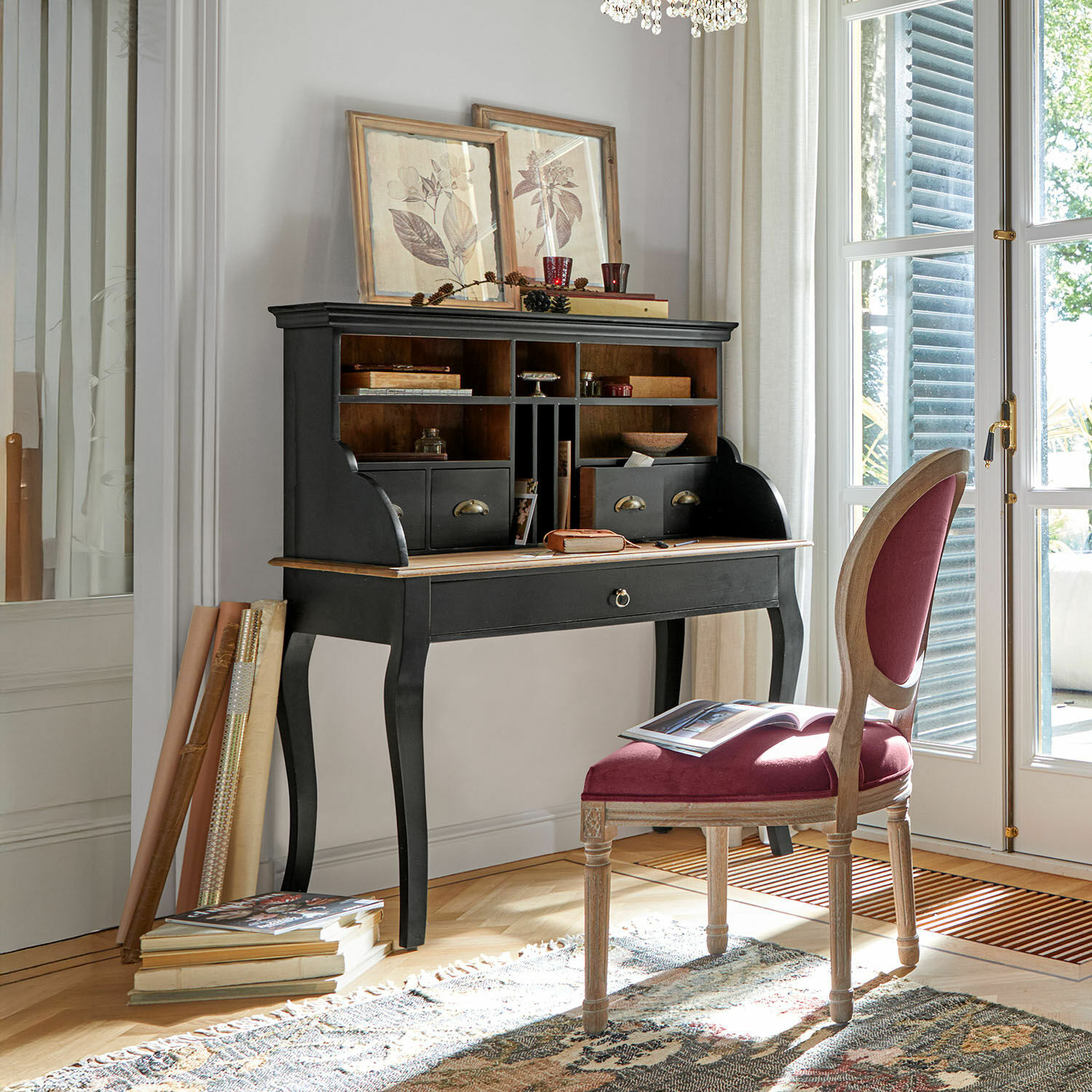 Zwart houten secretaire met laden en vakken in lichte kamer met stoel en boeken