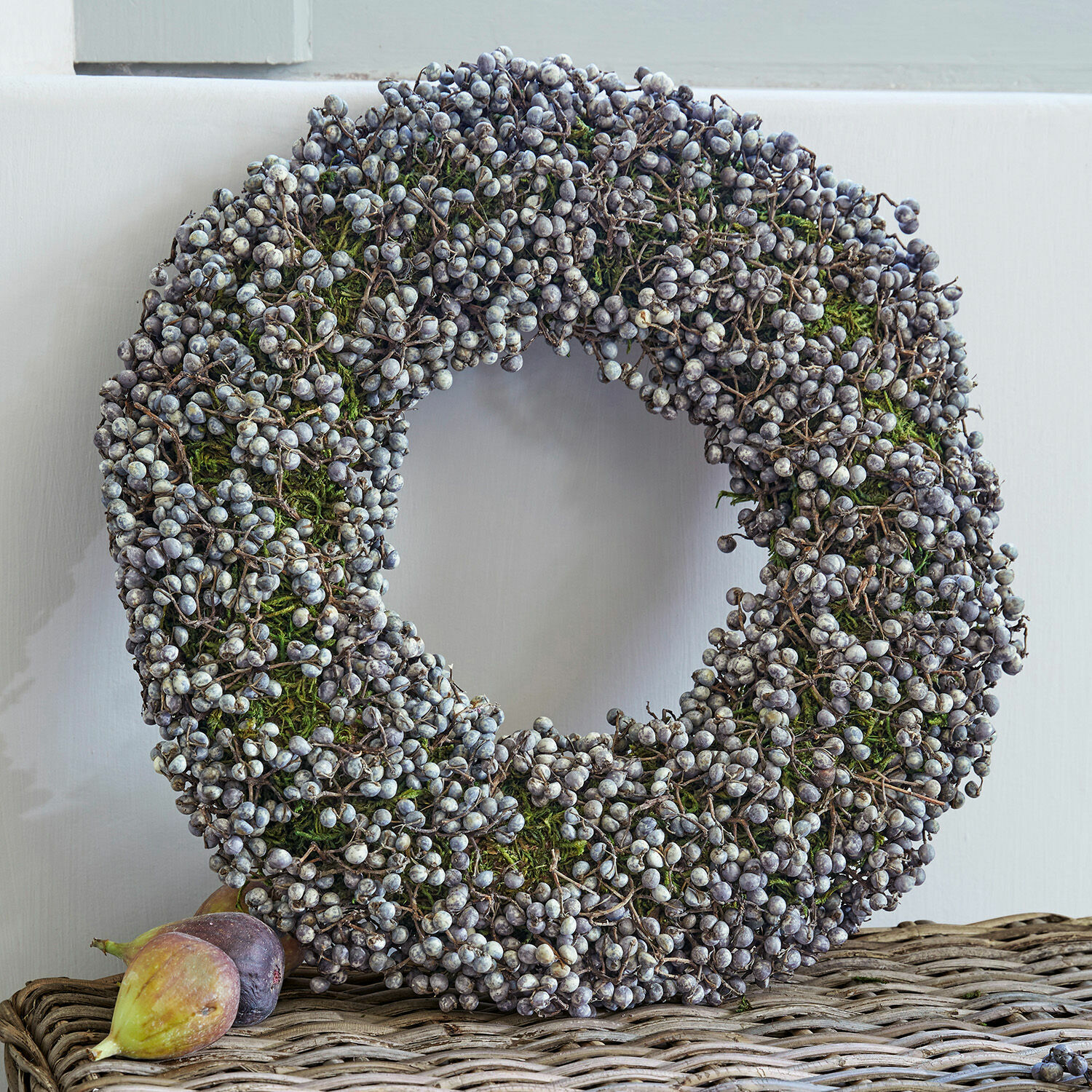 Krans Elly Decoratieve krans van gedroogde bessen en groen mos op een rieten tafel, seizoensdecoratie