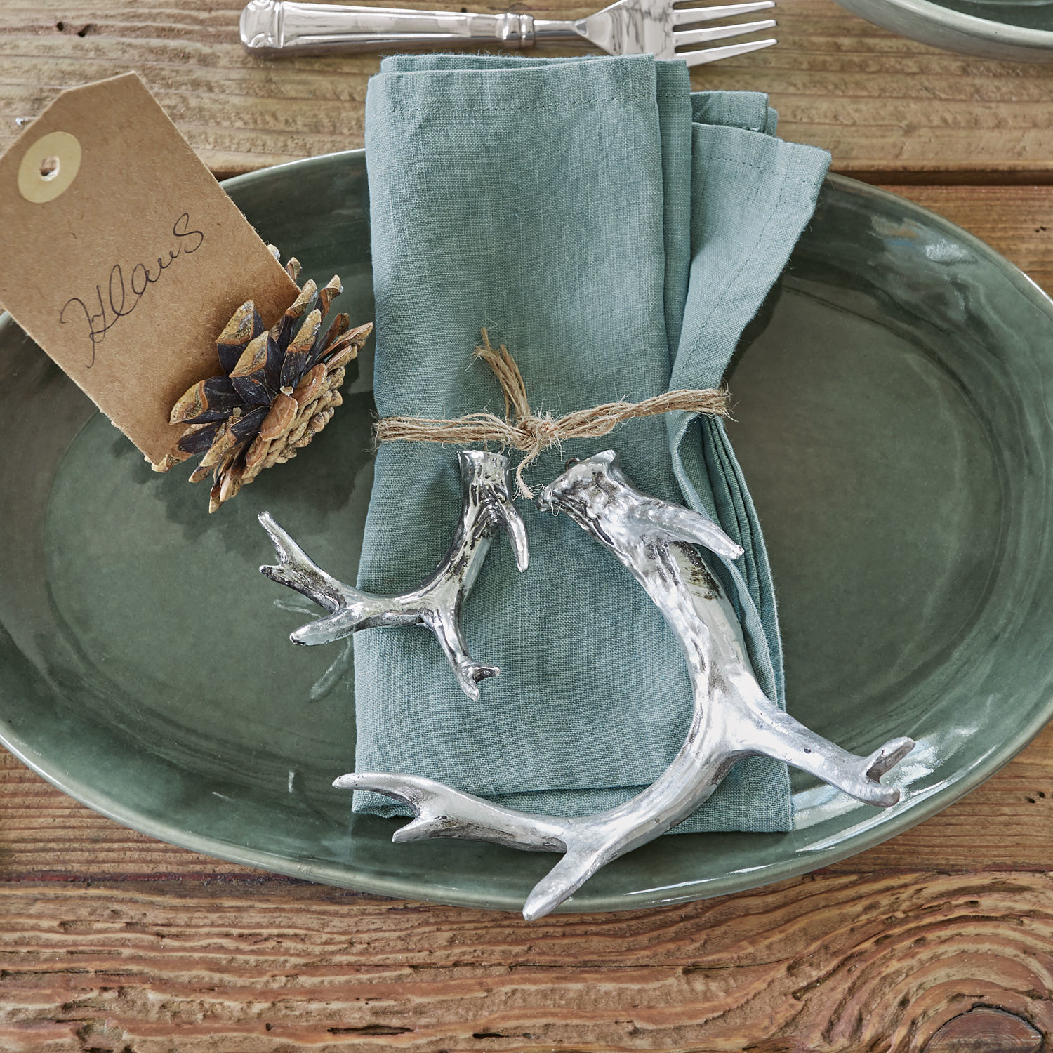 Groene keramische schaal met linnen servet en zilverkleurige gewei decoraties op houten tafel