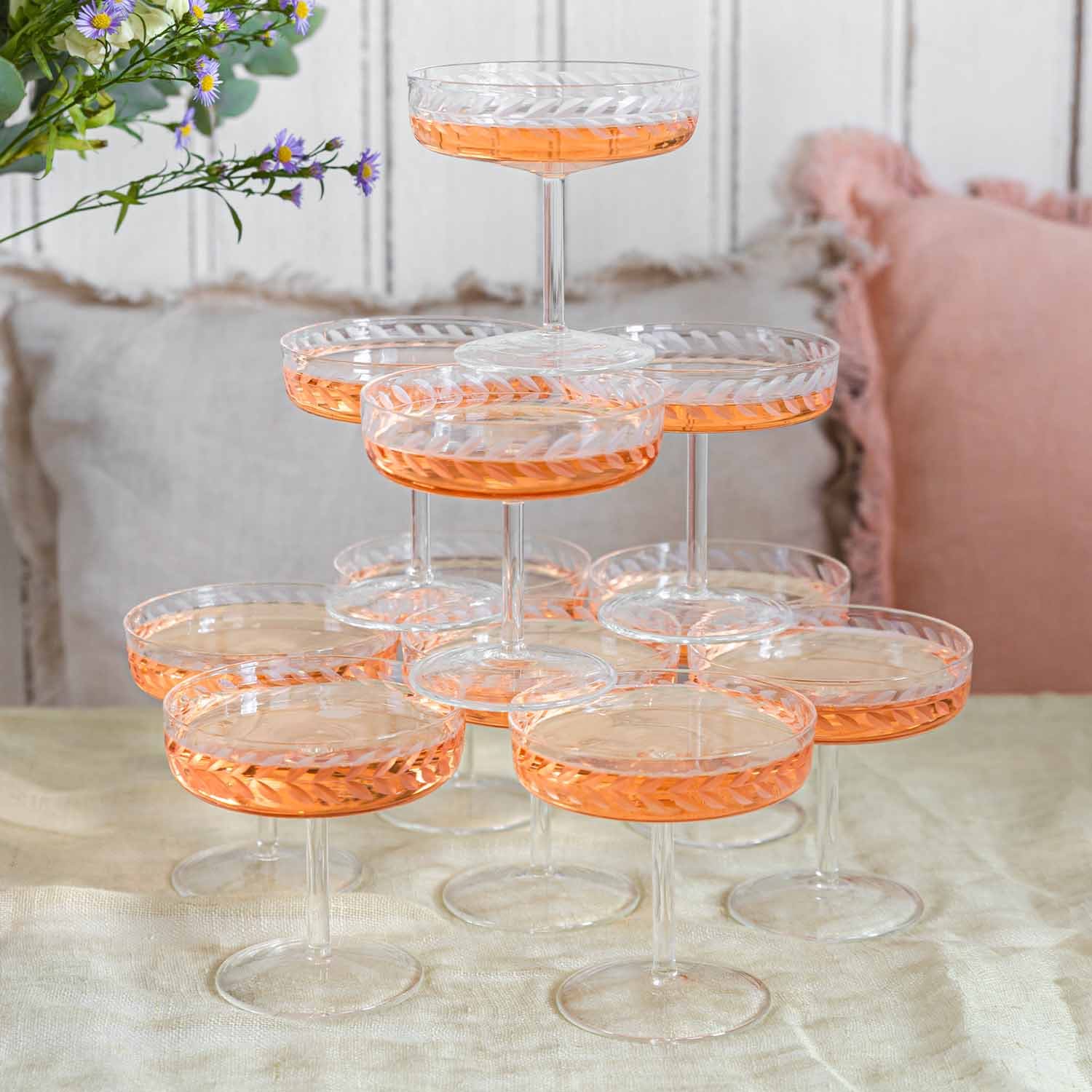 Set kristallen champagneglazen met fijn patroon en roze drankje op tafel
