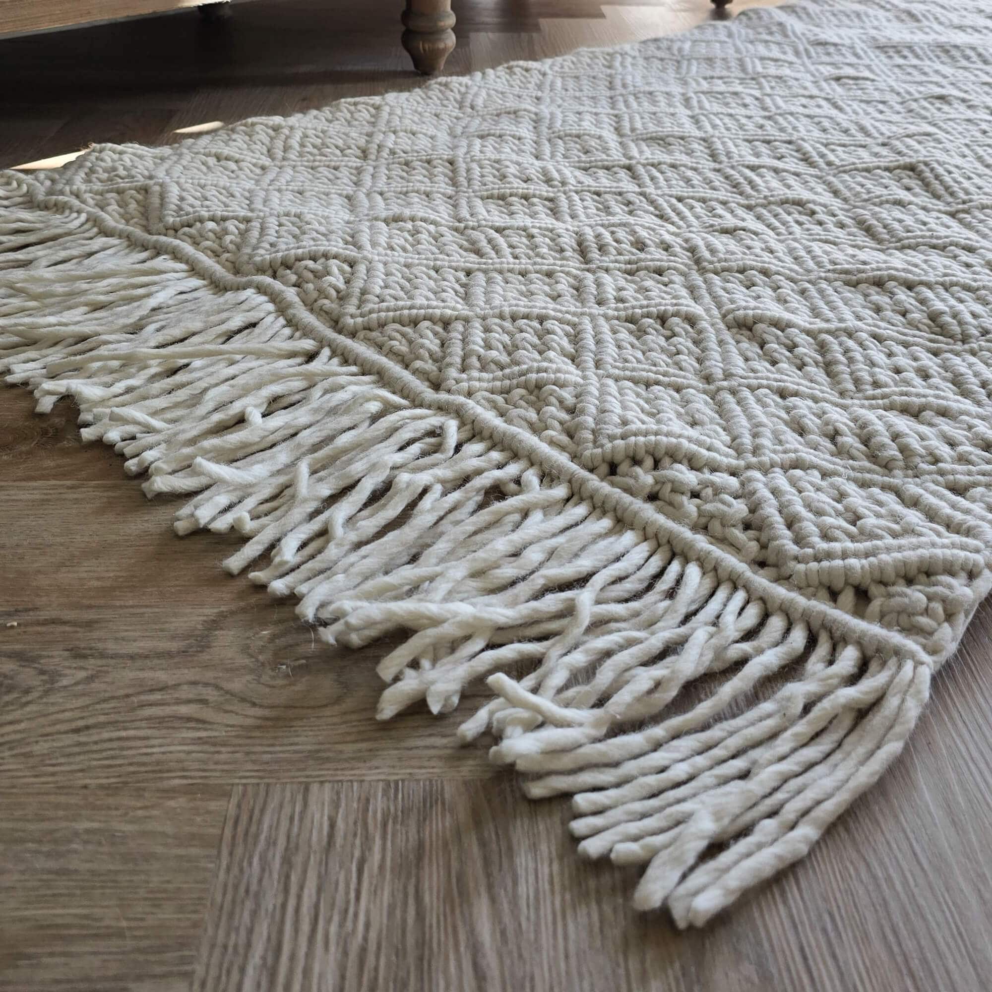 Witte wollen vloerkleed met grove structuur en franjes op houten vloer, zacht en decoratief
