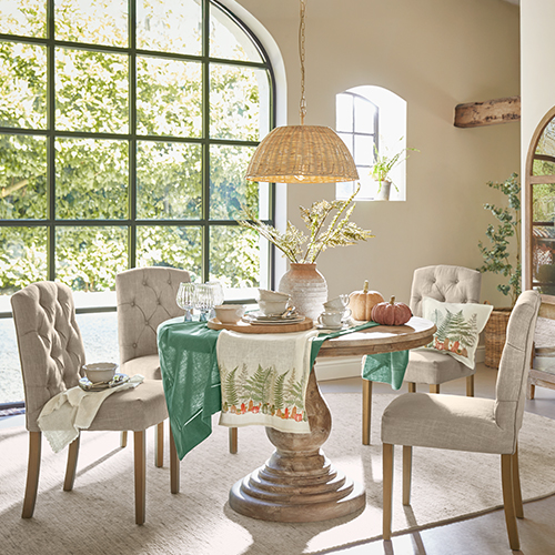 Eetkamer met ronde houten tafel en beige gestoffeerde stoelen, natuurlijke decoratie en daglicht