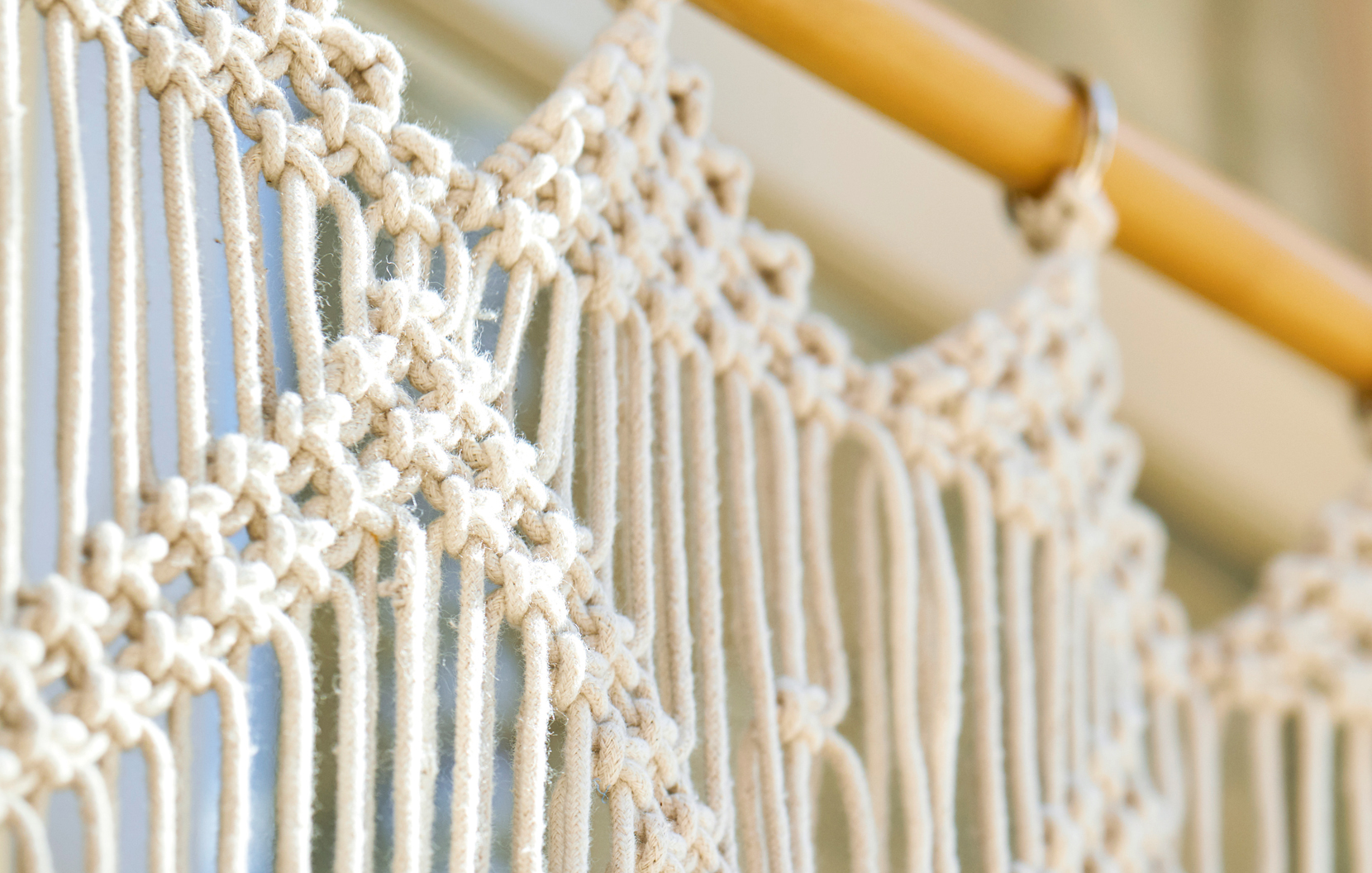 Wanddecoratie van natuurlijk katoenen macramé aan houten stok, boho stijl