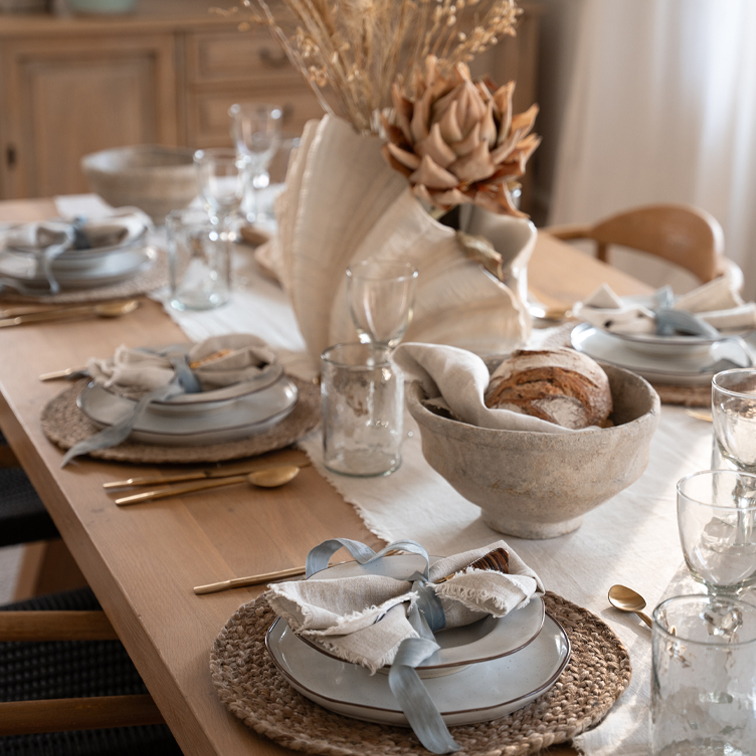 Rustieke houten tafel met keramische borden, linnen servetten en gedroogde bloemen als decoratie
