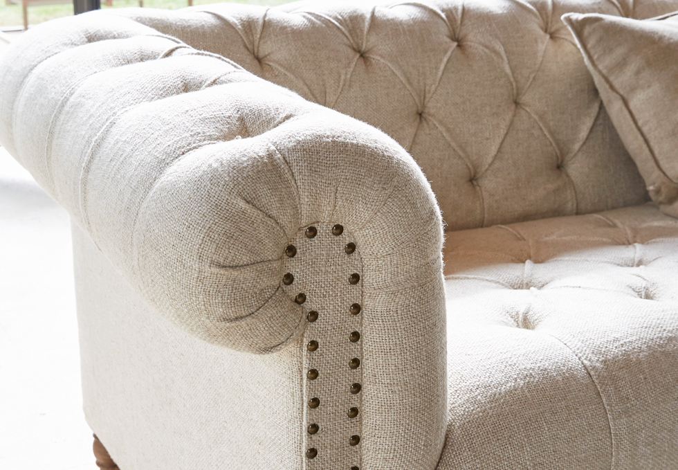 Beige klassieke stoffen bank met doorgestikte rugleuning en decoratieve nagels voor woonkamer