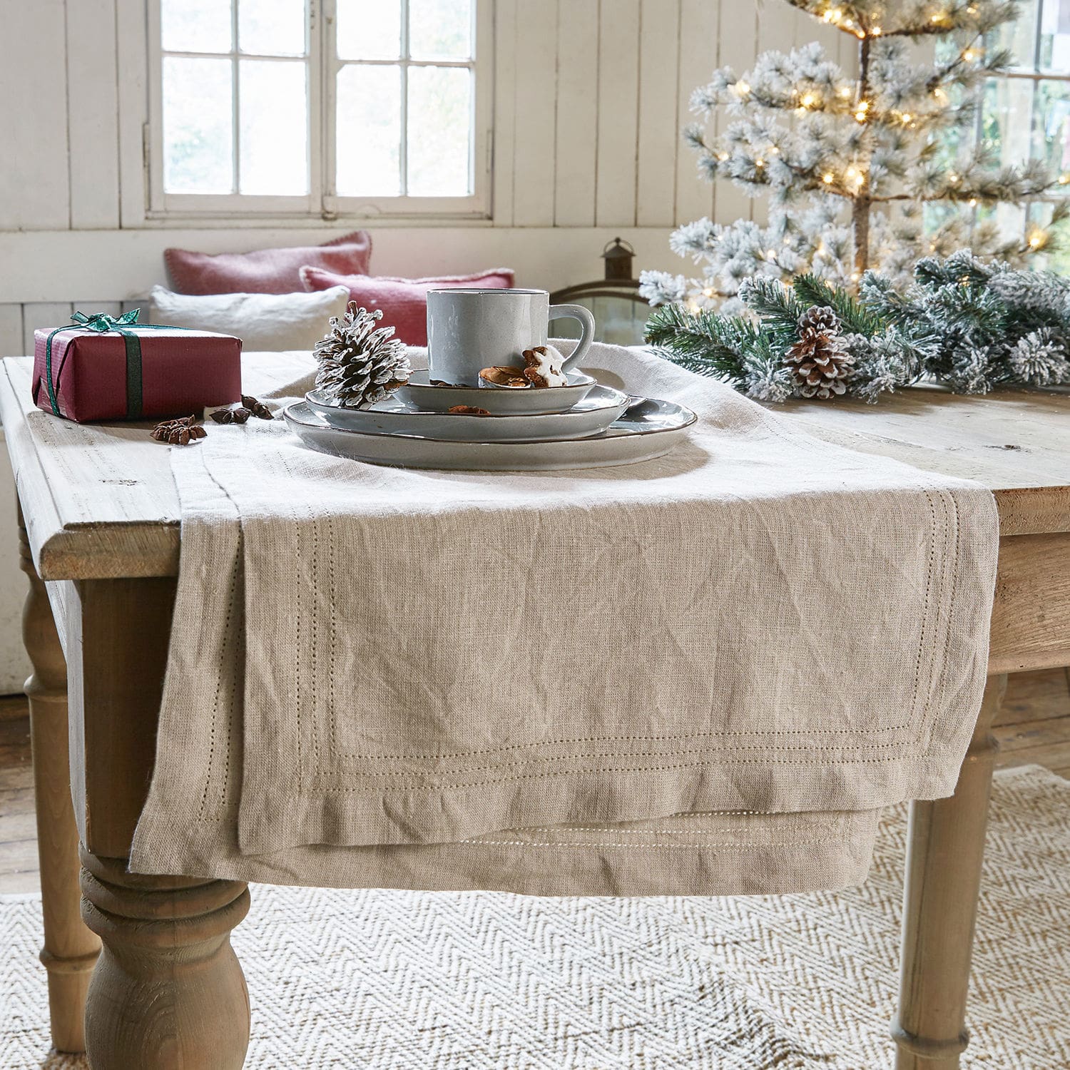 Tafelloper Brion Beige linnen tafelloper op houten tafel met kerstdecoratie en grijs servies