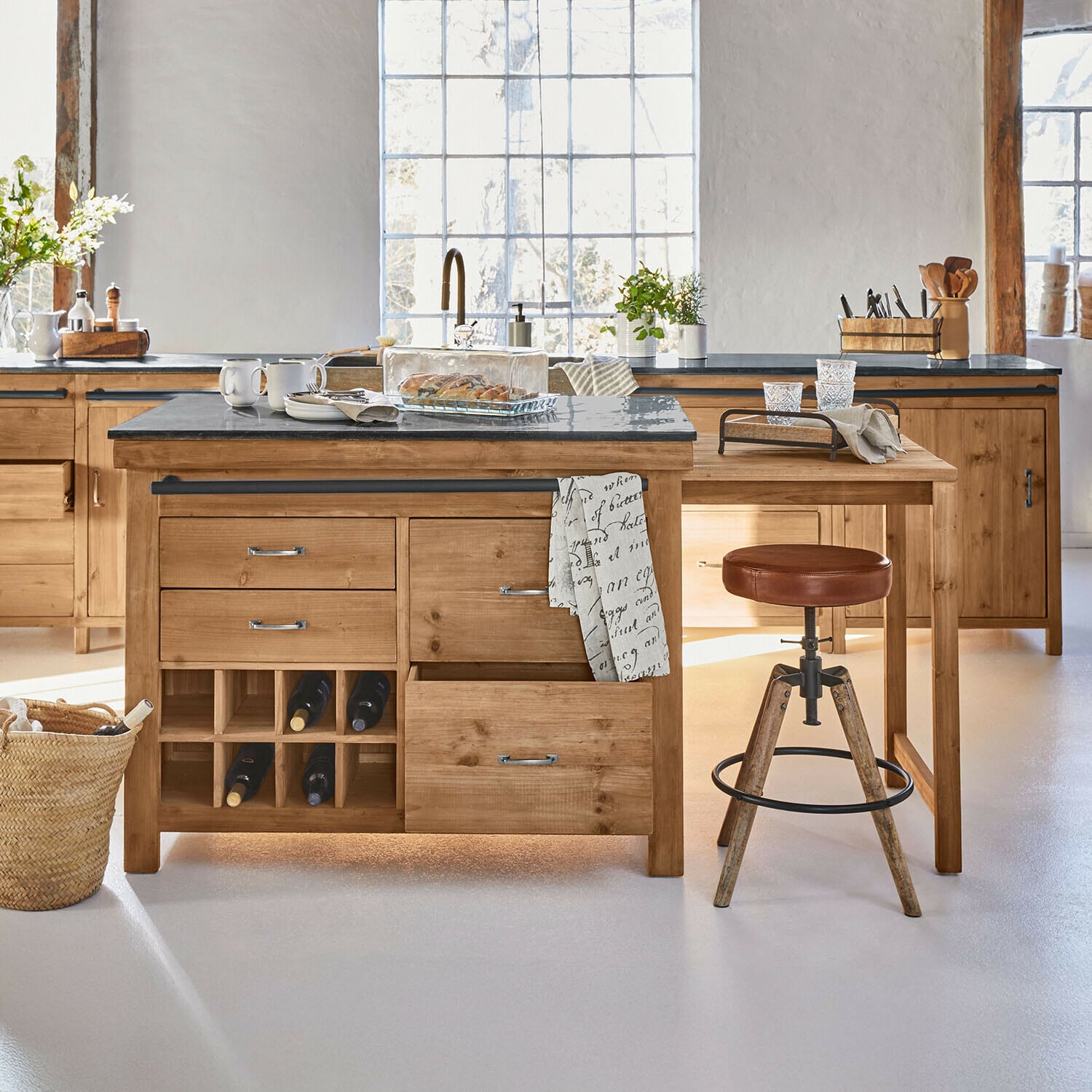 Keuken met houten eiland en zwart stenen werkblad, wijnopslag en kruk met bruine leren zitting