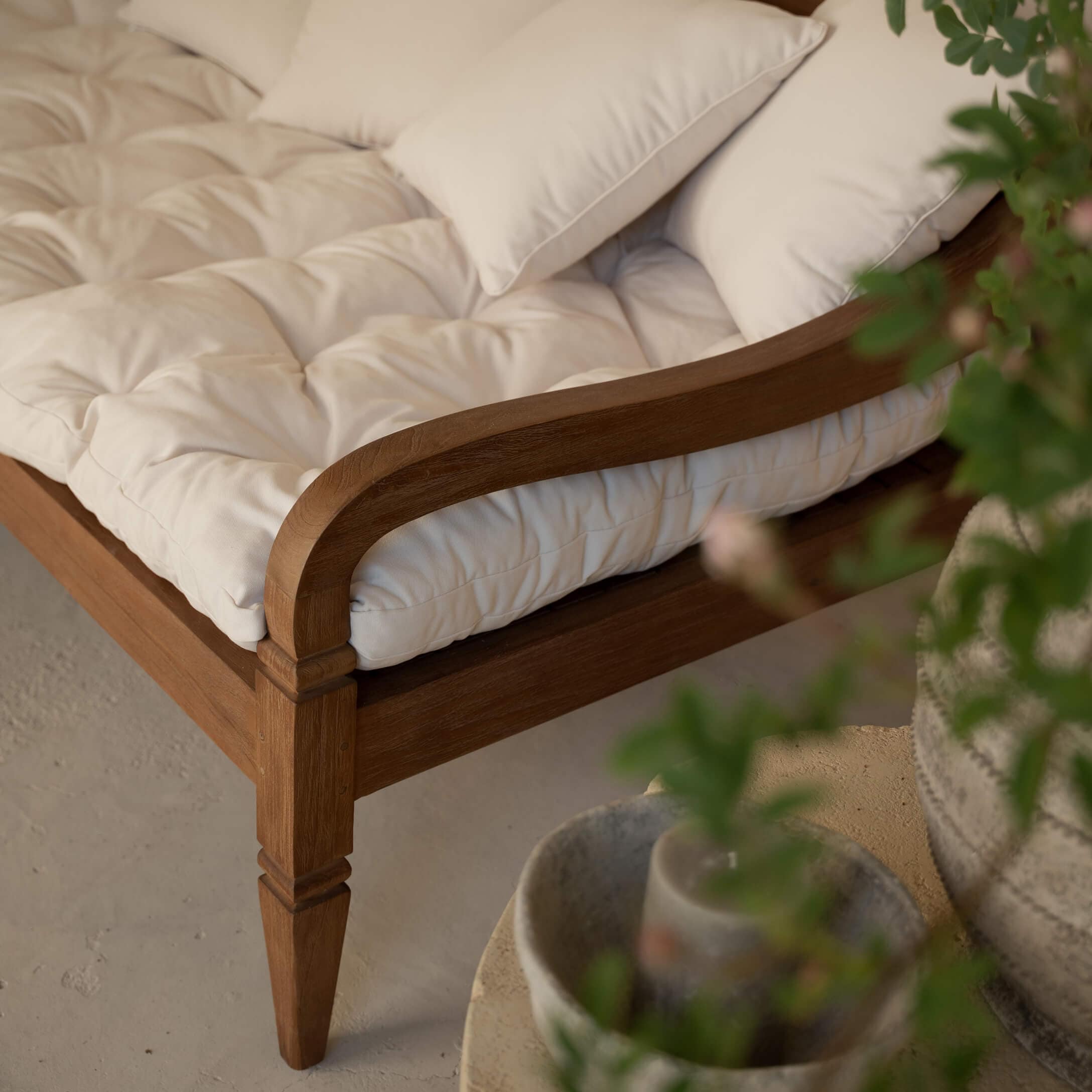 Houten bankframe met crèmekleurig doorgestikt kussen en zachte sierkussens