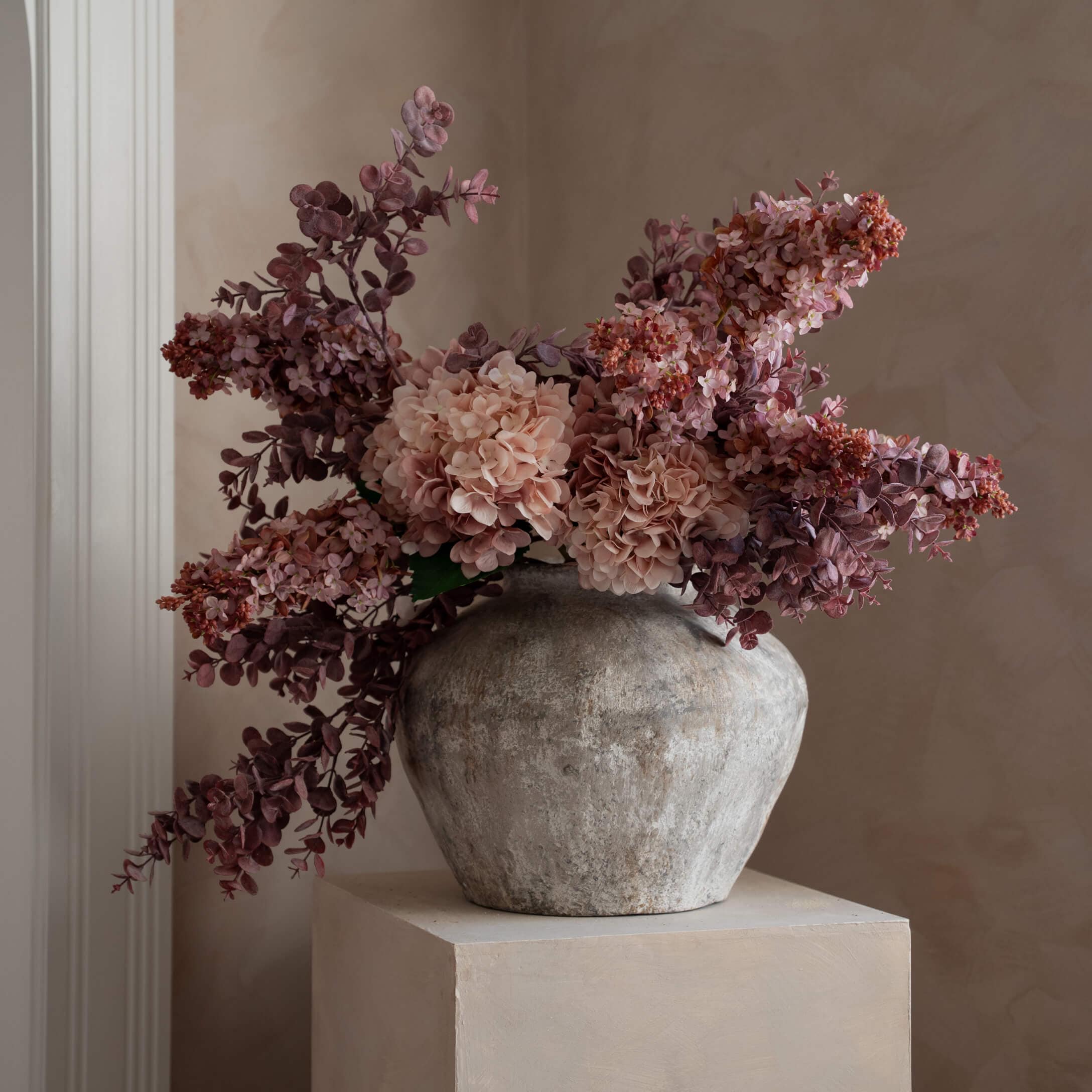 Decoratieve grijze stenen vaas met roze en paarse kunstbloemen voor interieurdecoratie