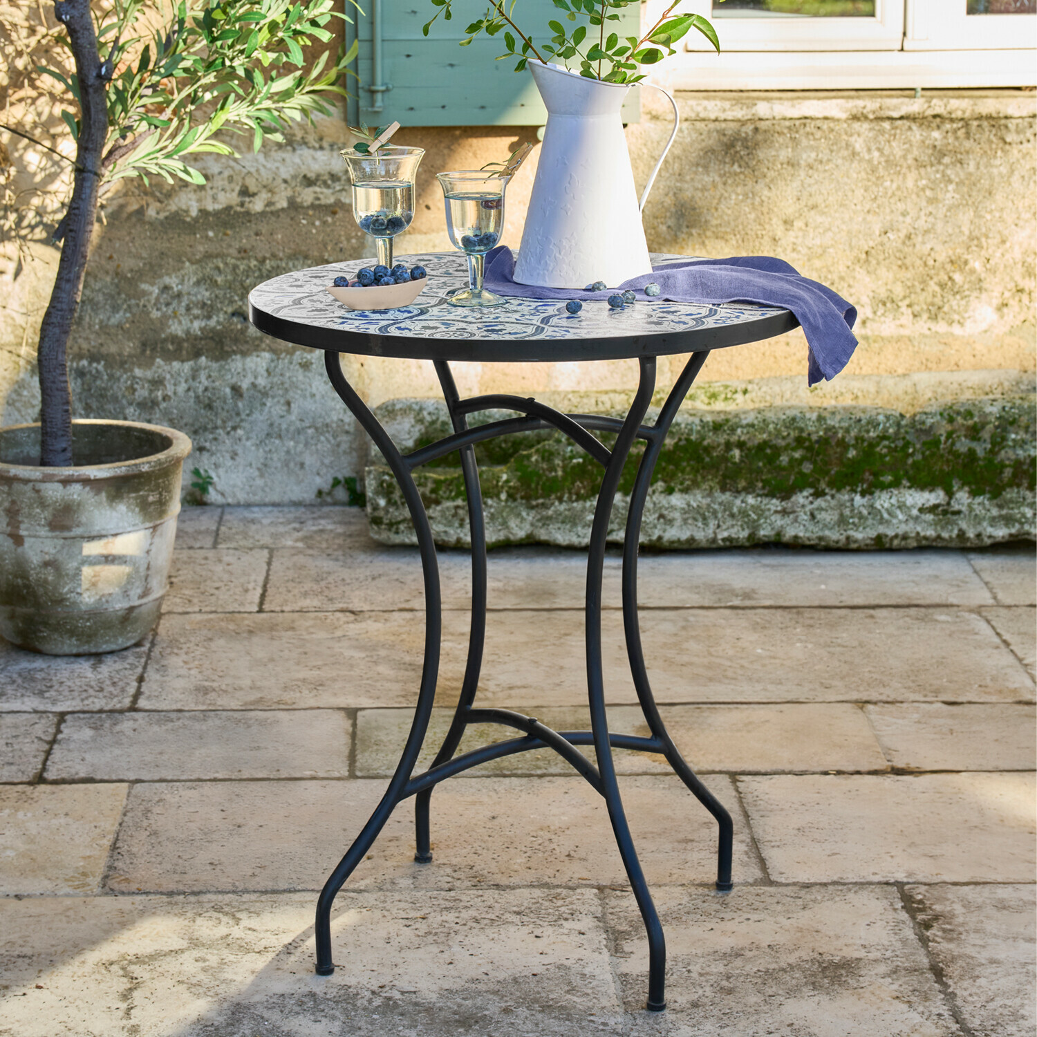 Ronde tuintafel met zwart metalen onderstel en blauw-wit mozaïek tafelblad buiten