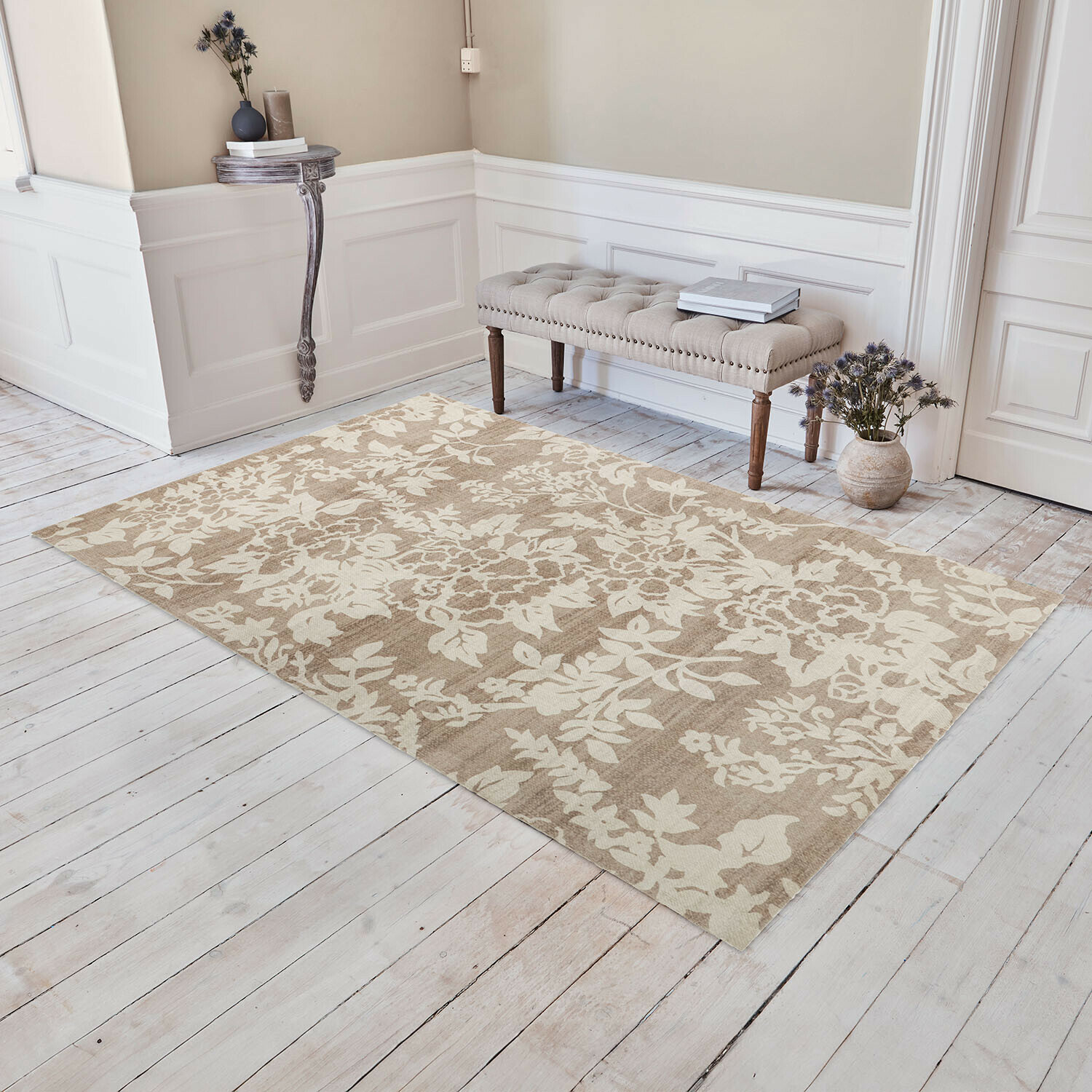 Beige vloerkleed met bloemmotief op lichte houten vloer in elegante kamer met gestoffeerde bank