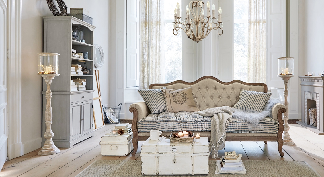 Shabby chic woonkamer met beige bank, witte houten kisten en grijze vitrinekast