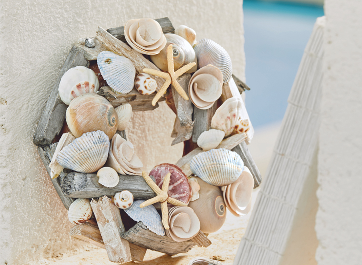 Decoratieve krans van hout en schelpen in beige en lichtblauwe tinten, maritieme woonstijl.