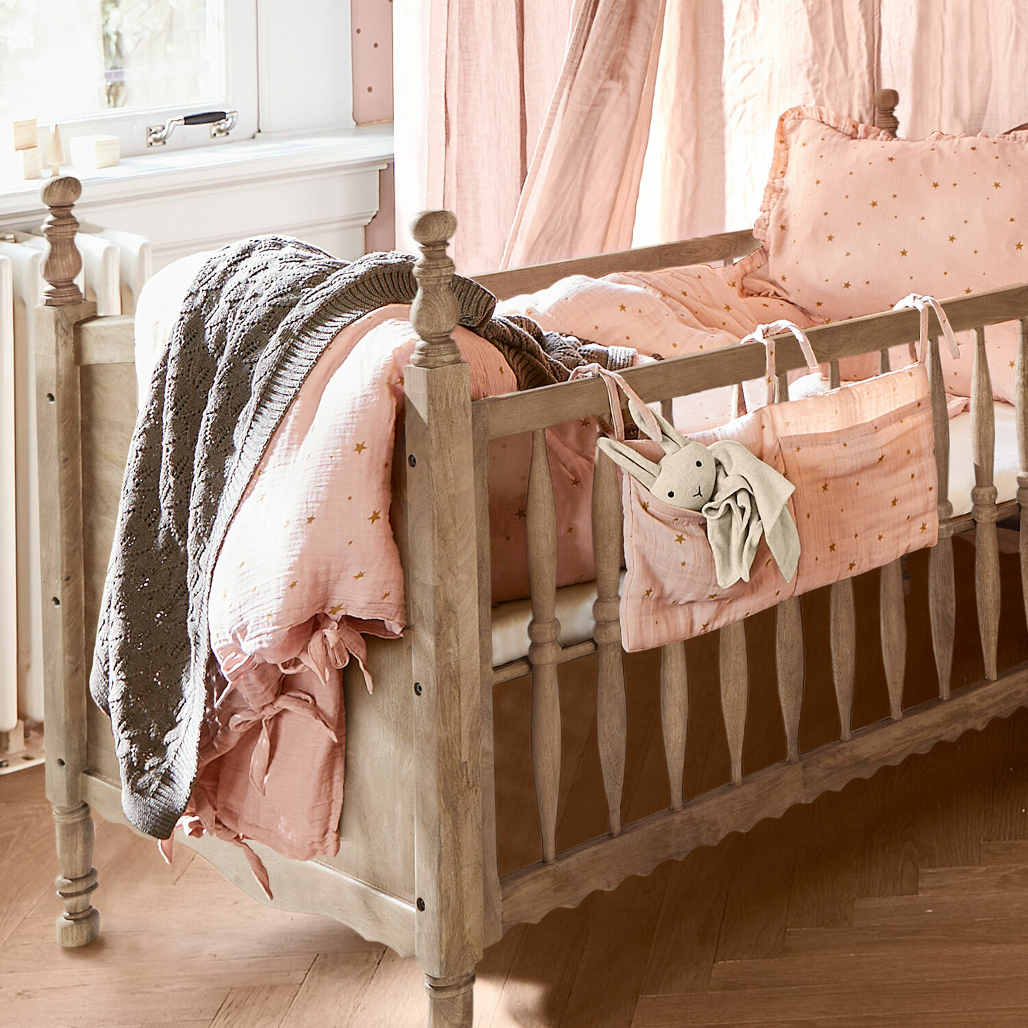 Dekbedovertrekset voor een babybedje Vianne Houten babybed met roze sterrenbeddengoed en grijze deken, gezellige kinderkamer