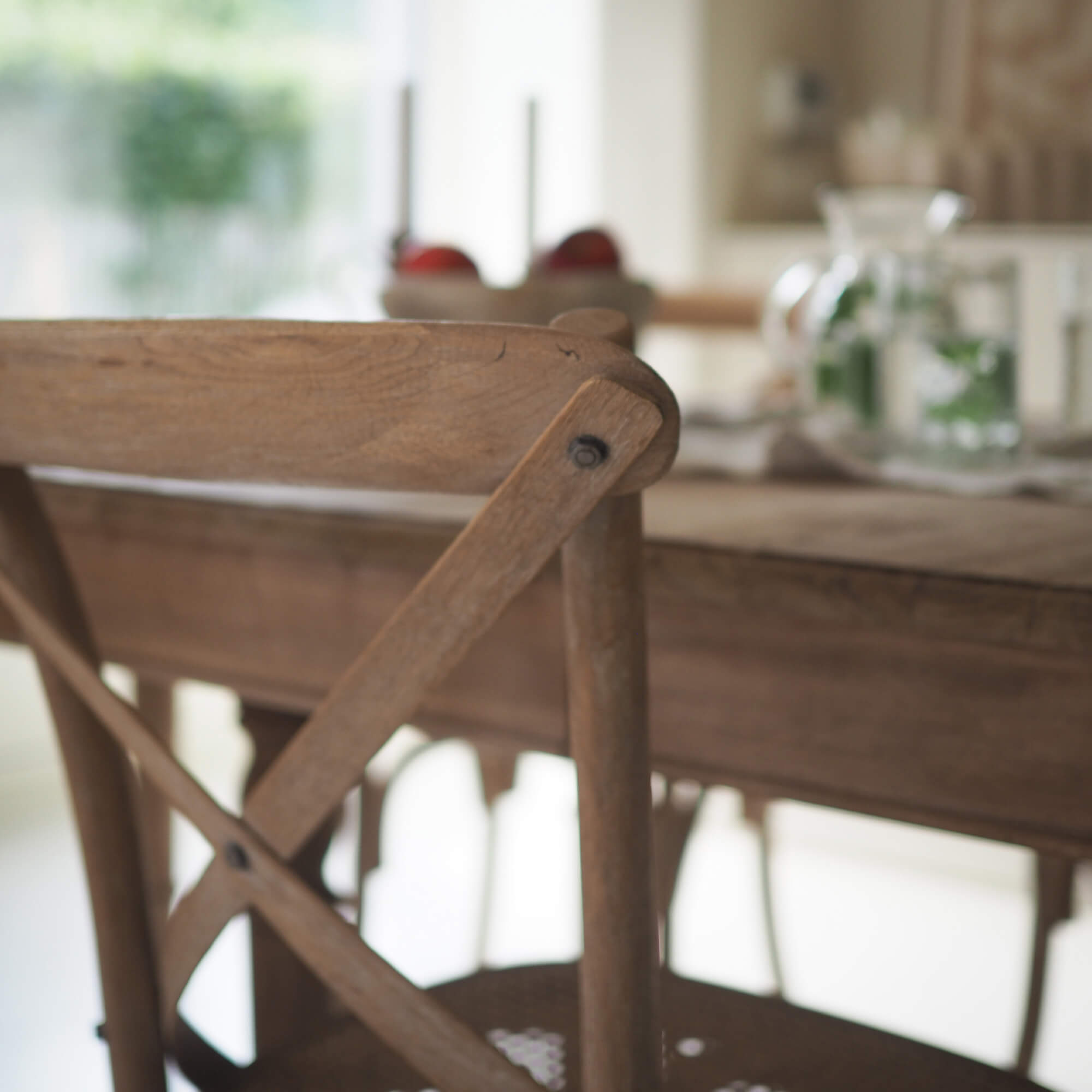 Houten stoel met X-vormige rugleuning in lichte bruine kleur in een gezellige eetkamer