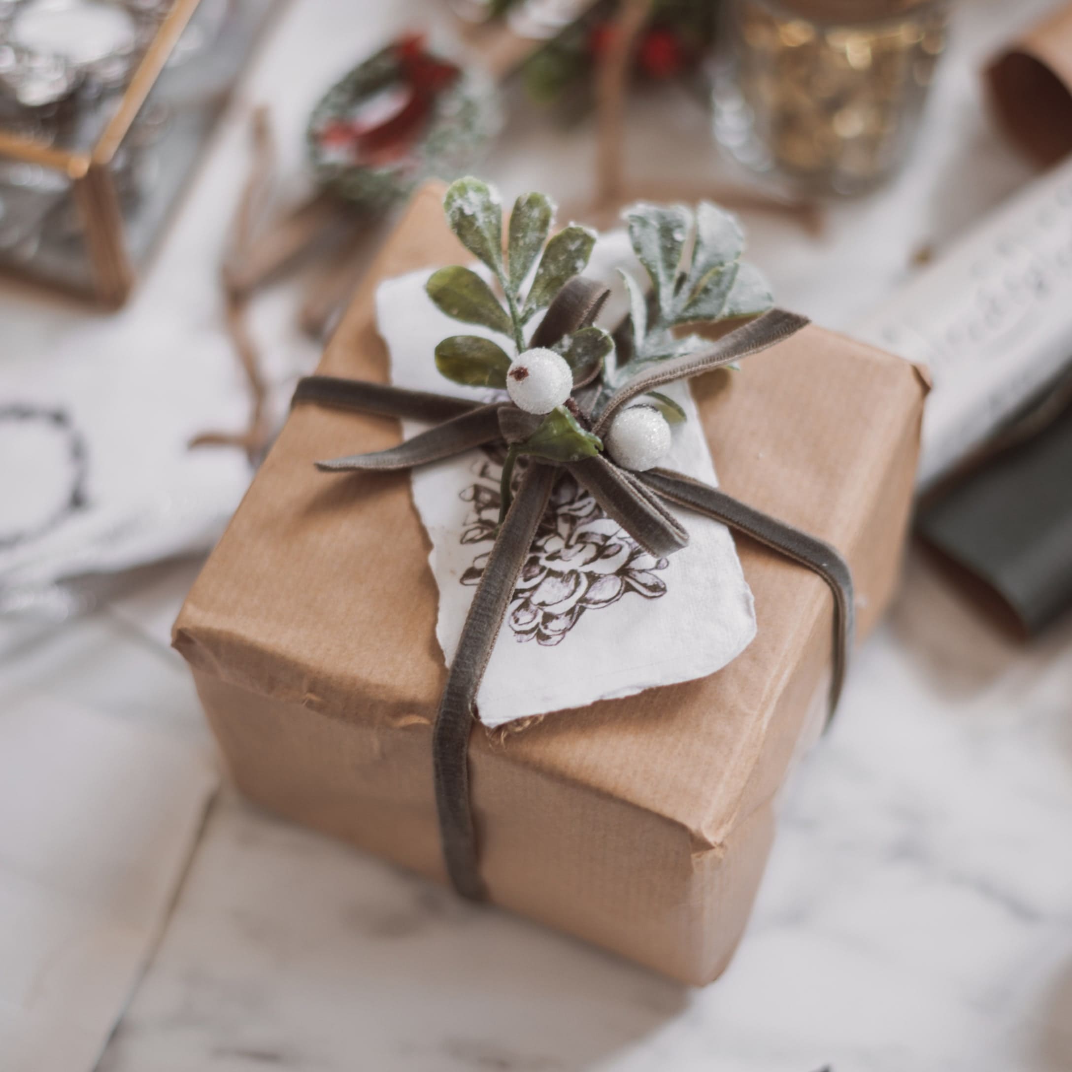 Cadeau verpakt in bruin papier met decoratieve tak en witte bessen op een fluwelen lint