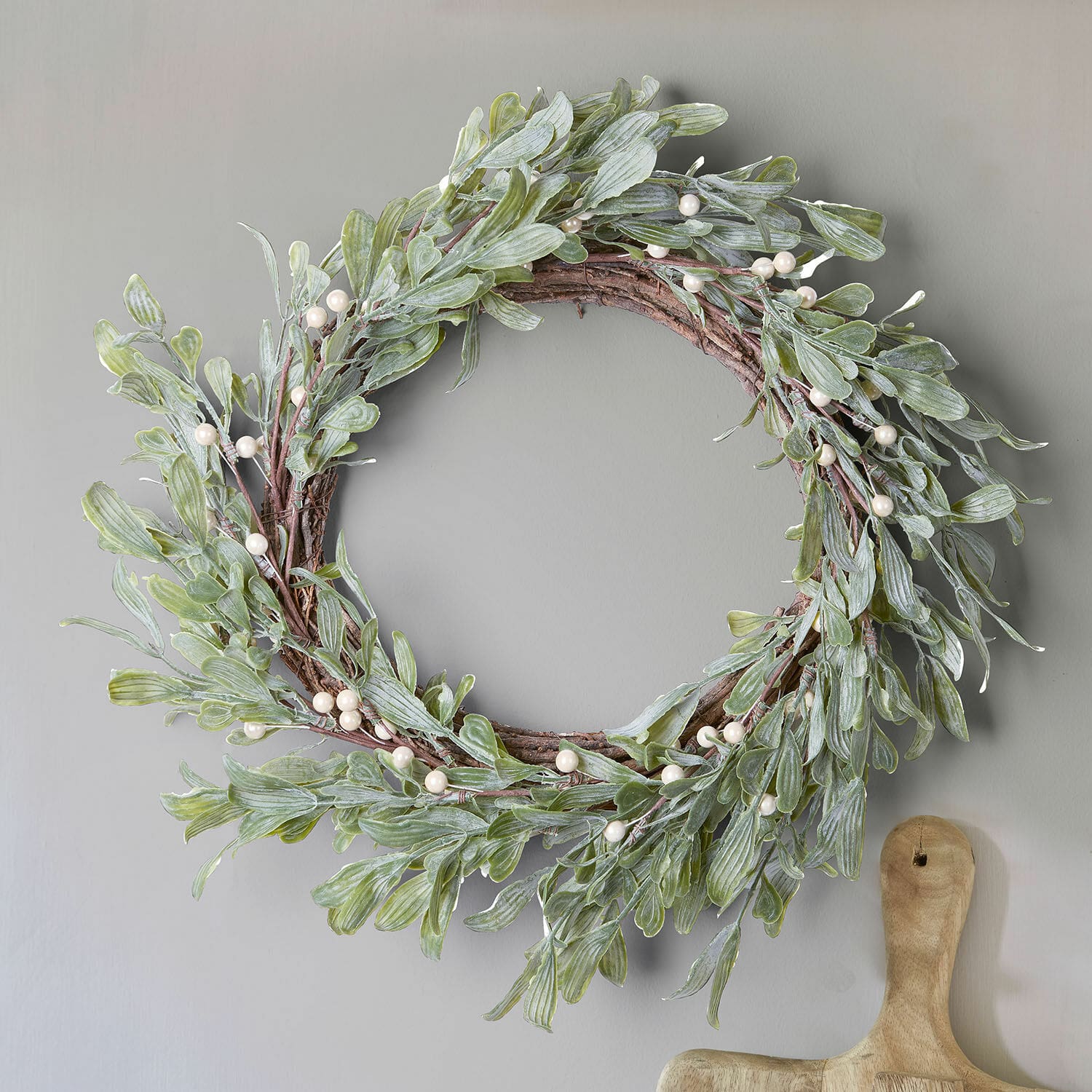 Decoratieve krans met groene bladeren en witte parels op houten basis voor binnen