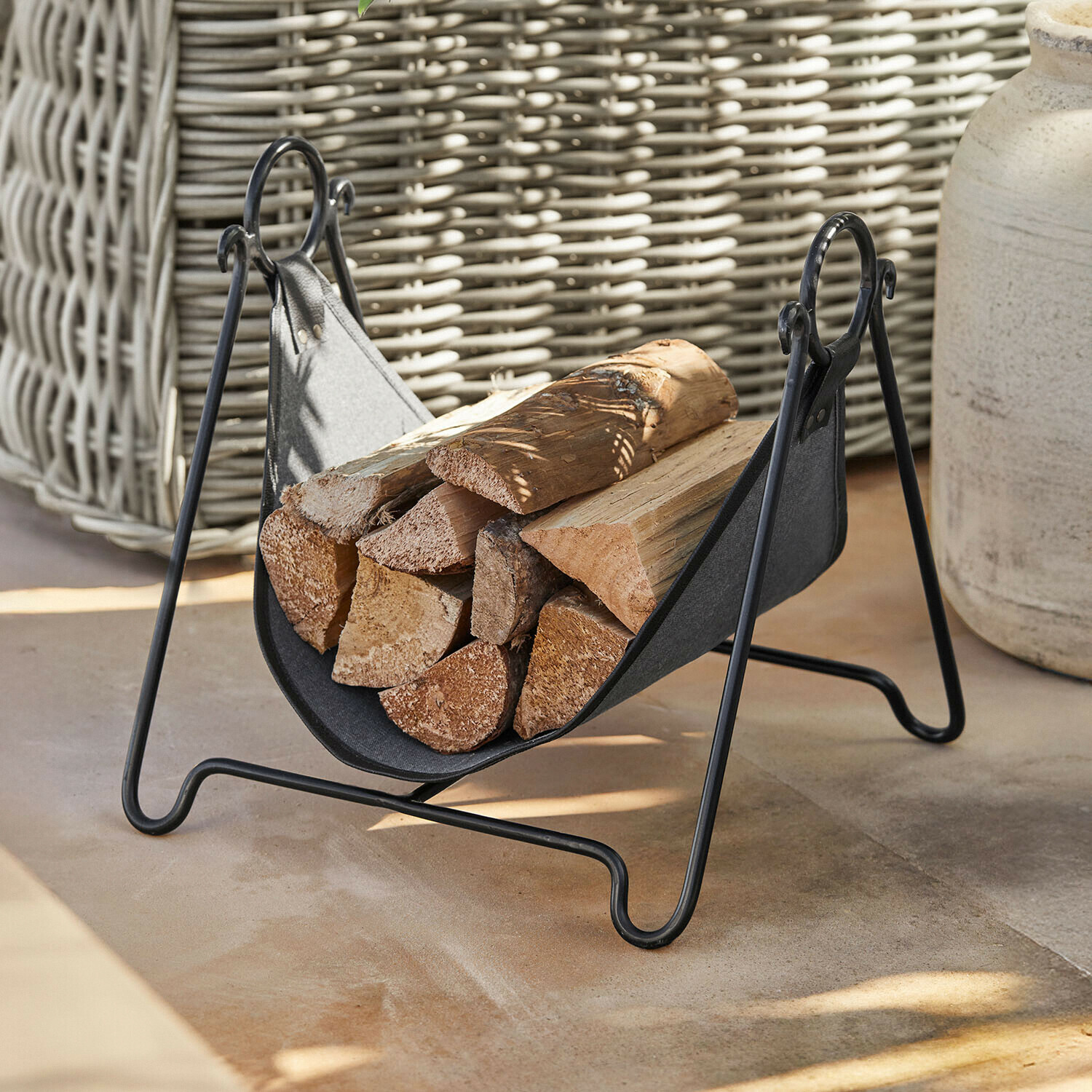 Zwarte metalen houtdrager met stof en brandhout, praktisch voor open haard