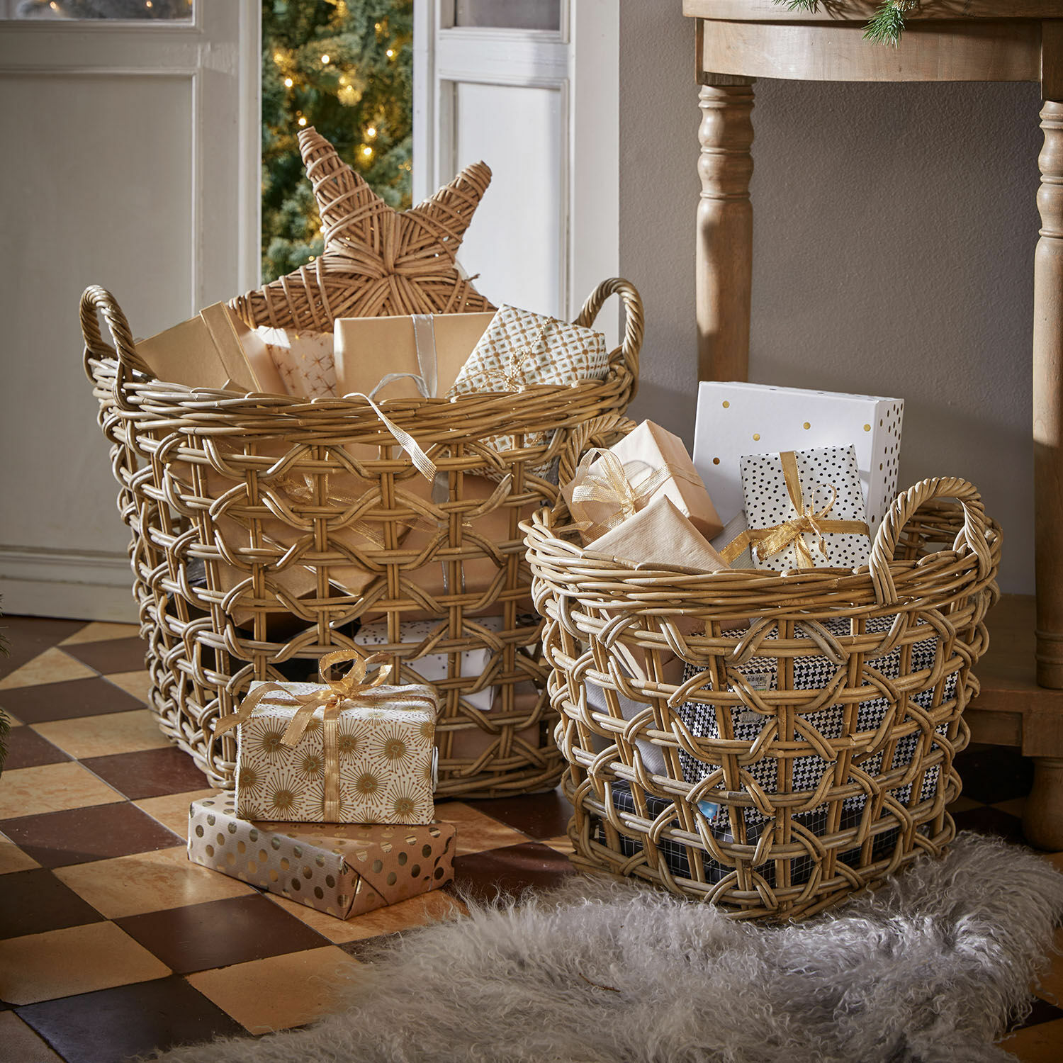 Twee natuurlijke rieten manden met cadeaus en kerstdecoraties op een betegelde vloer.