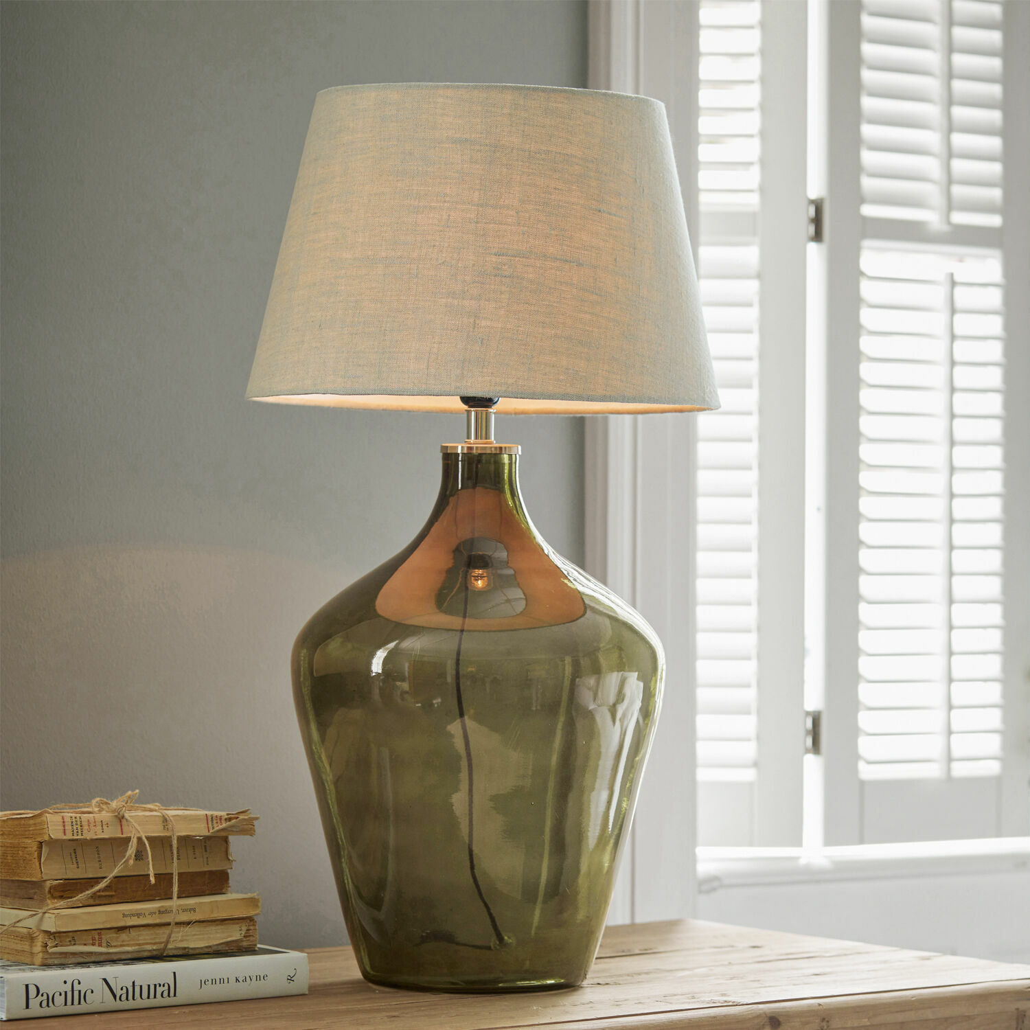 Tafellamp Morazan Tafellamp van groen glas met beige kap op houten tafel naast boeken