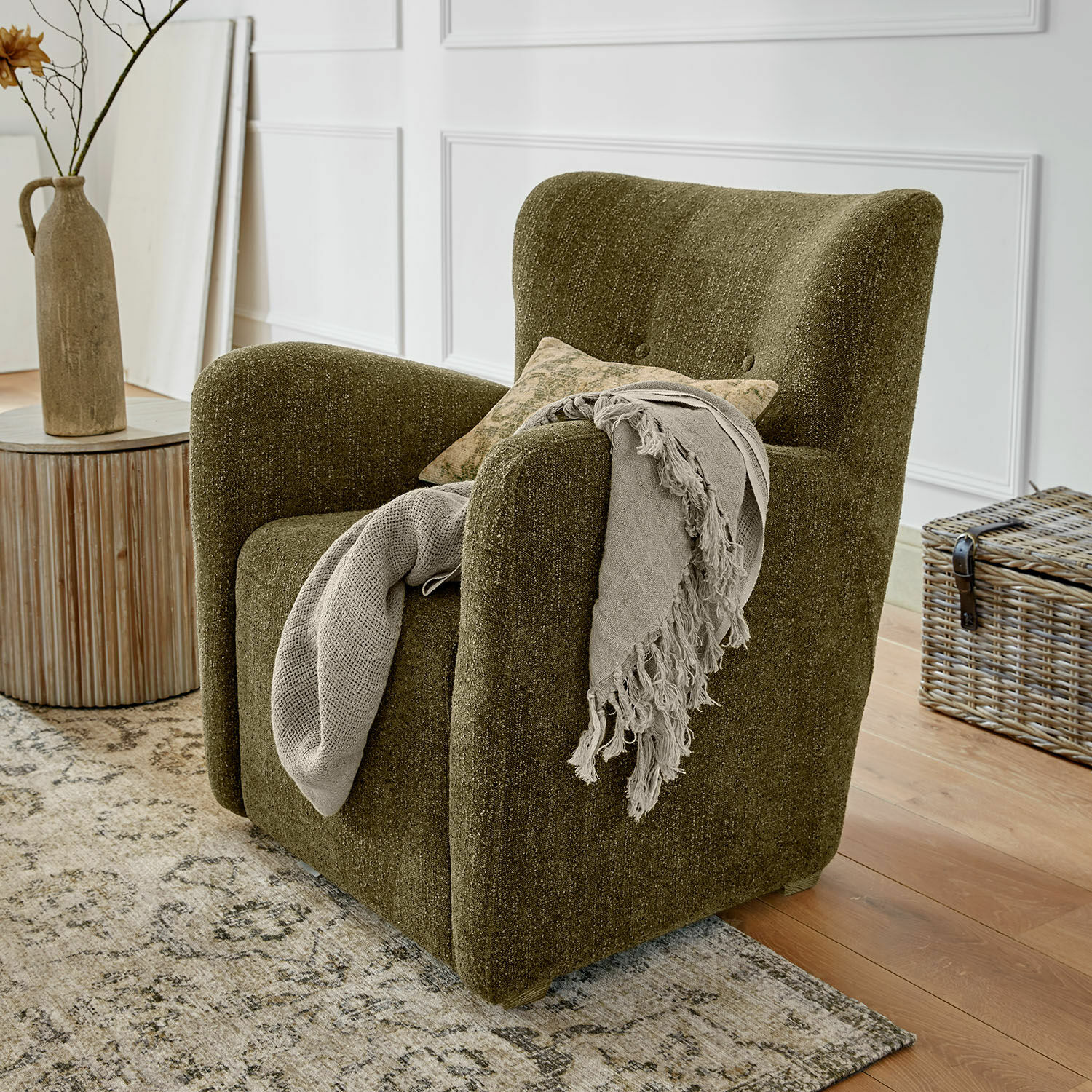 Groene gestoffeerde fauteuil van zachte stof in vintage stijl met decoratief plaid in woonkamer