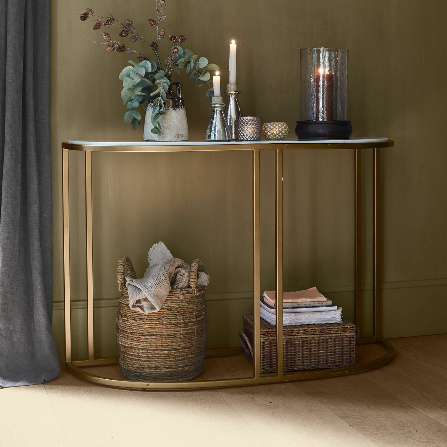 Consoletafel met wit marmeren blad en gouden metalen frame, gedecoreerd met kaarsen en vaas met groene bladeren