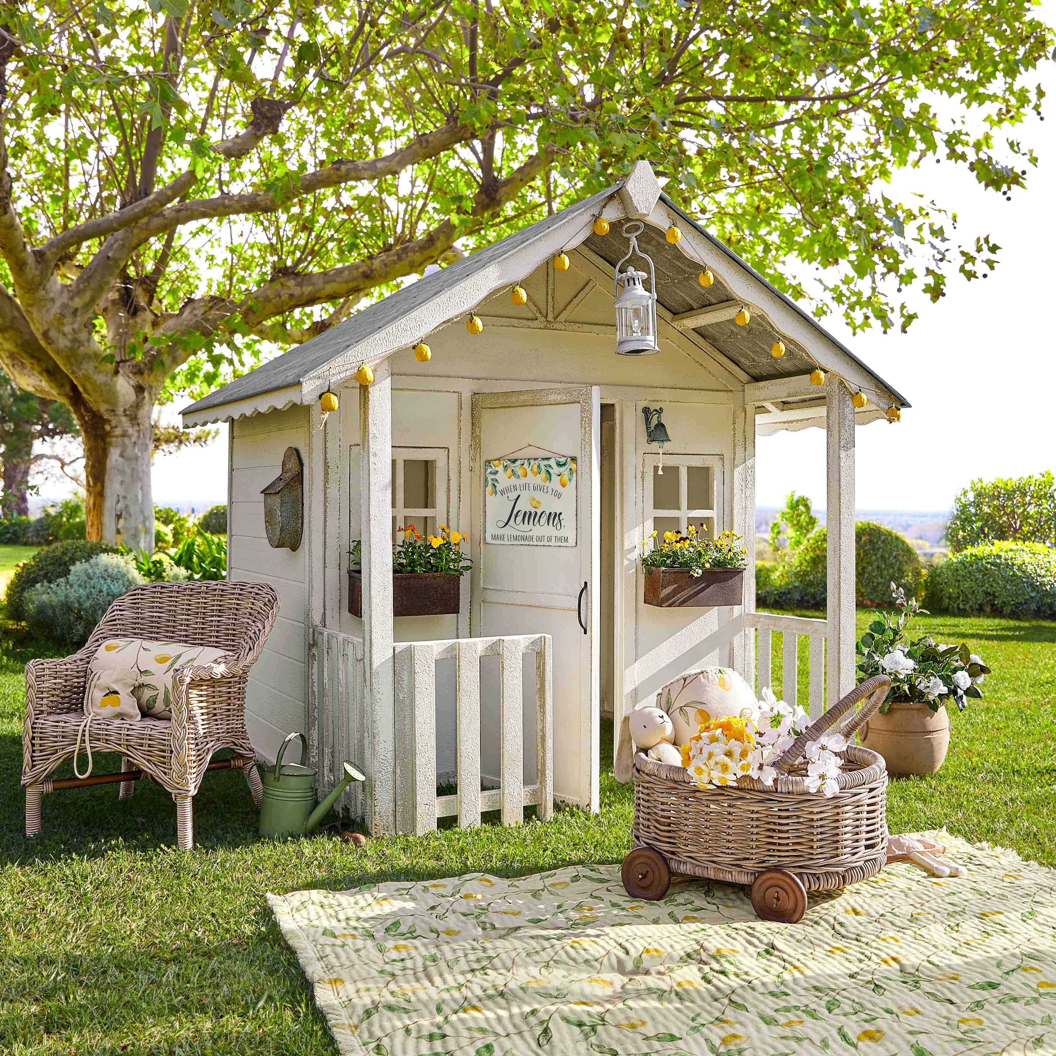 Witte houten tuinhuisje met decoratieve lampjes en bloemen op groen gras