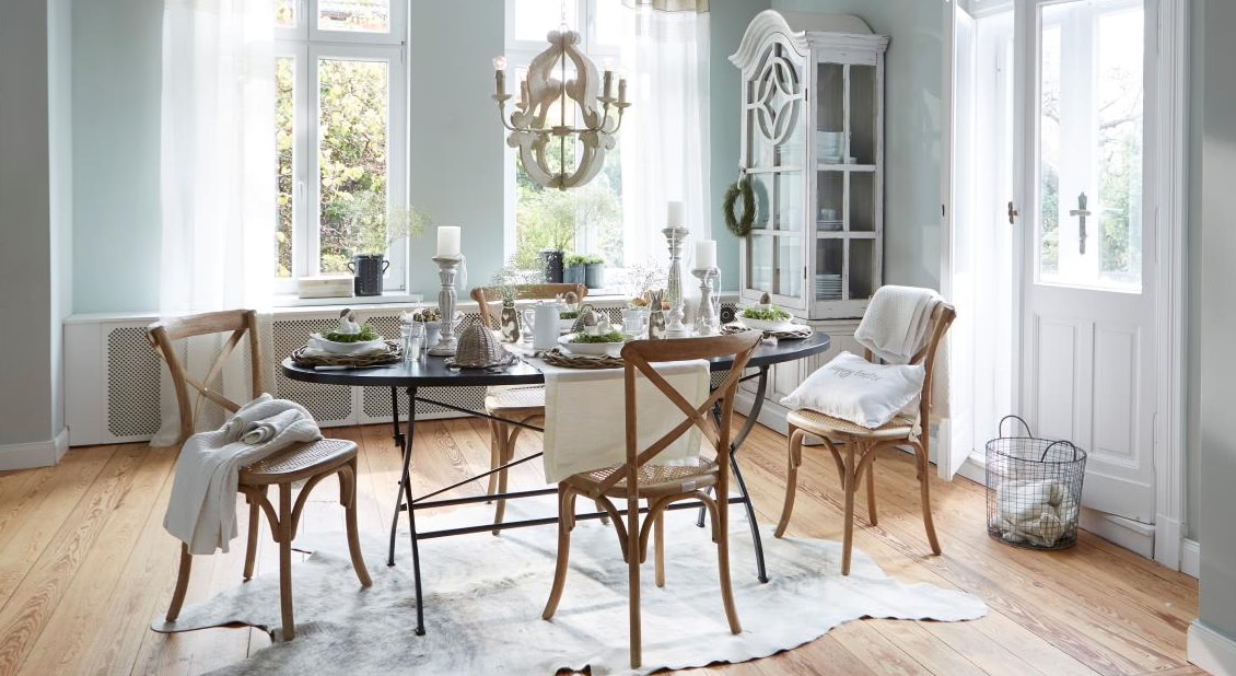 Eetkamer met zwarte metalen tafel en houten stoelen in lichte natuurlijke stijl met tafelversiering