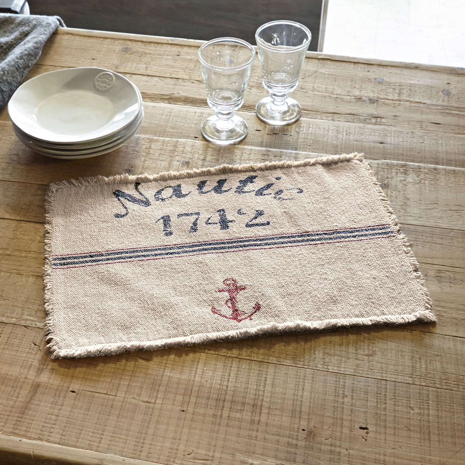 Placemat set van 2 Nautic Beige katoenen placemat met rode anker en tekst Nautic 1742 op houten tafel