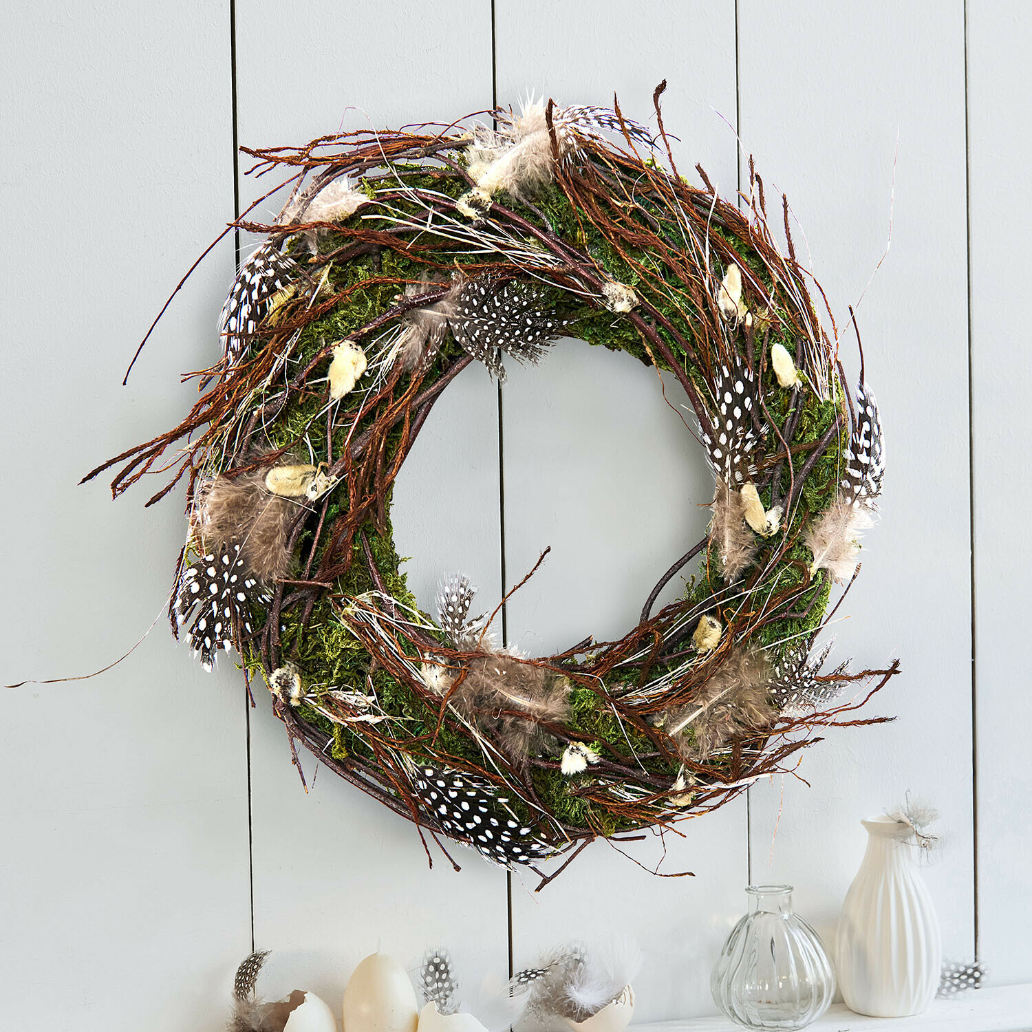 Decoratieve krans van takken, mos en veren in natuurlijke kleuren voor wanddecoratie