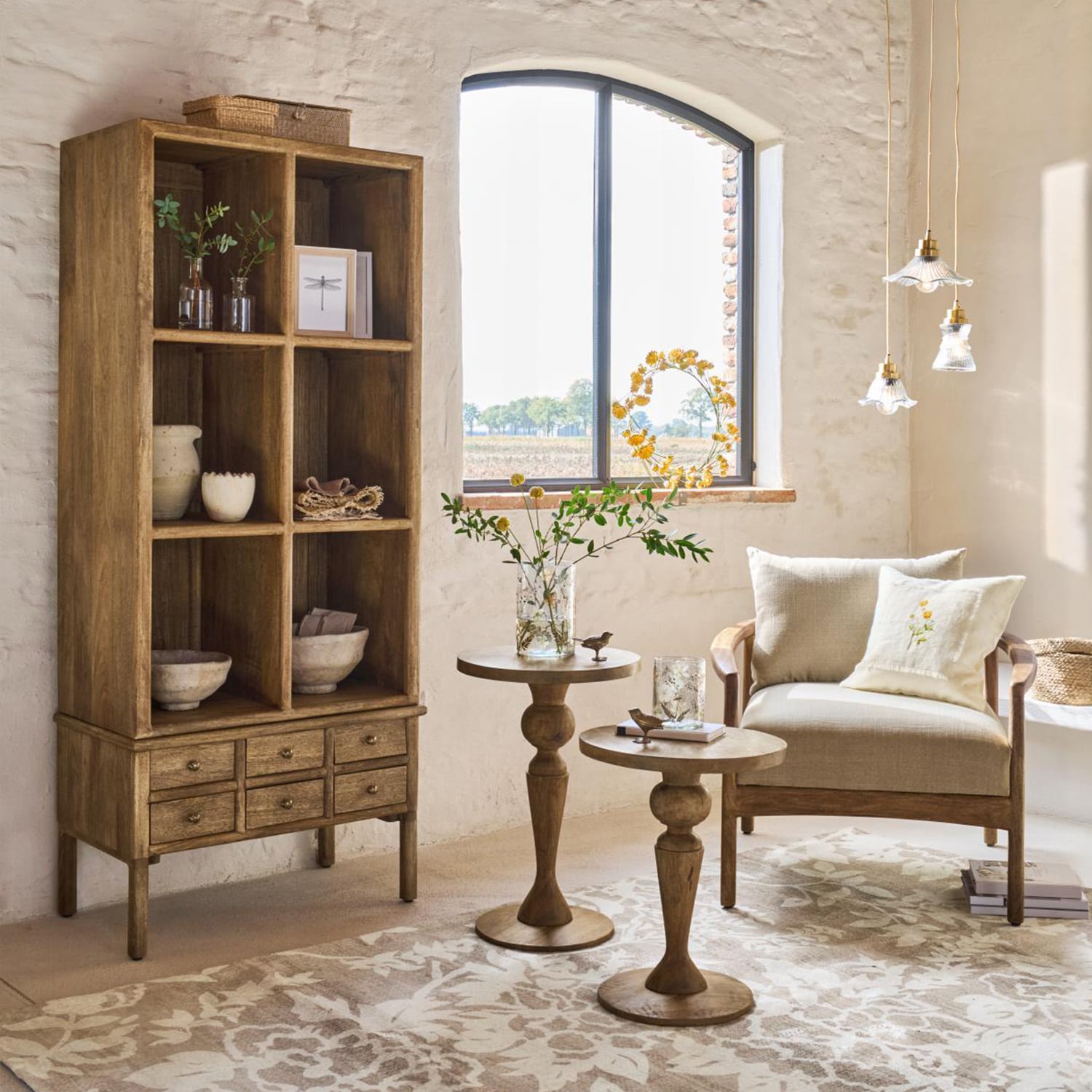 Houten kast met laden en bijzettafels in natuurlijke kleur in lichte woonkamer met beige fauteuil
