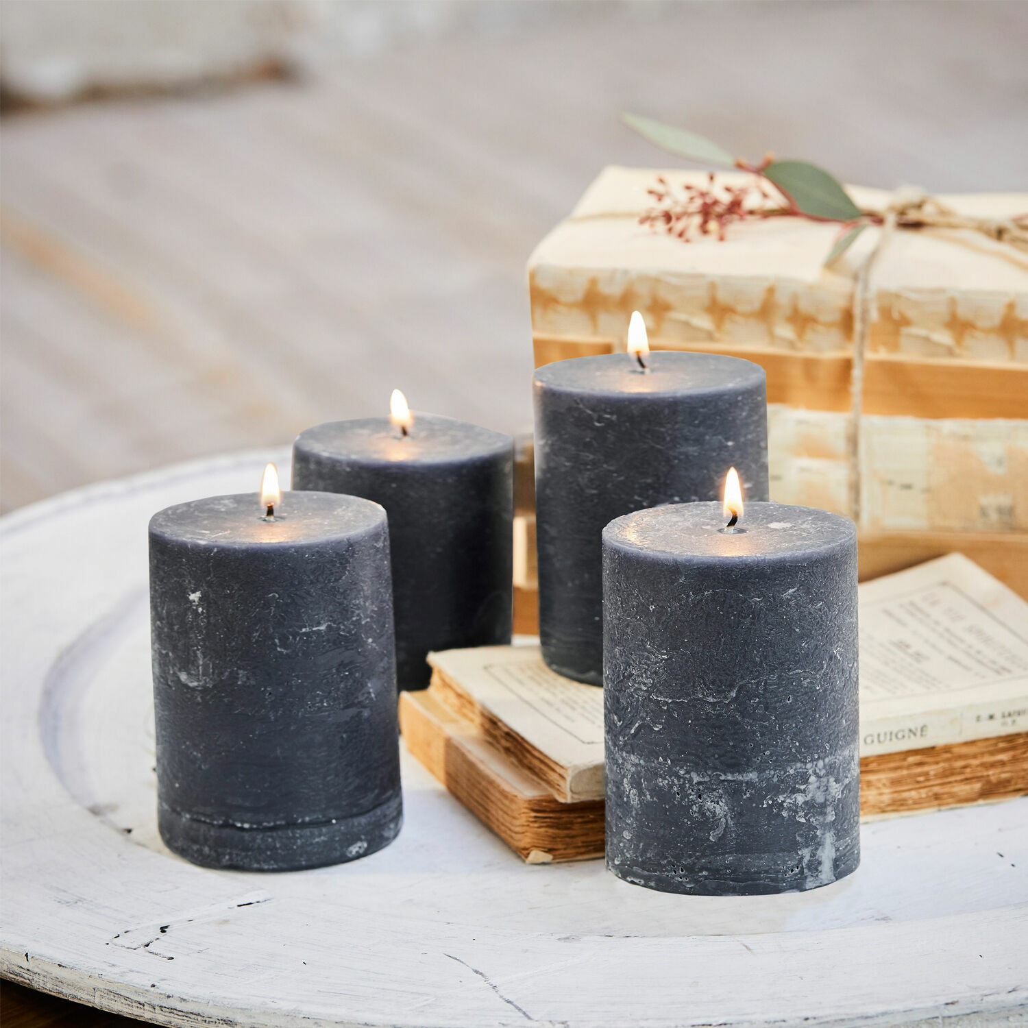 Kaars set van 4 Virrans Vier zwarte waskaarsen op een witte houten tafel met boeken en cadeau op de achtergrond