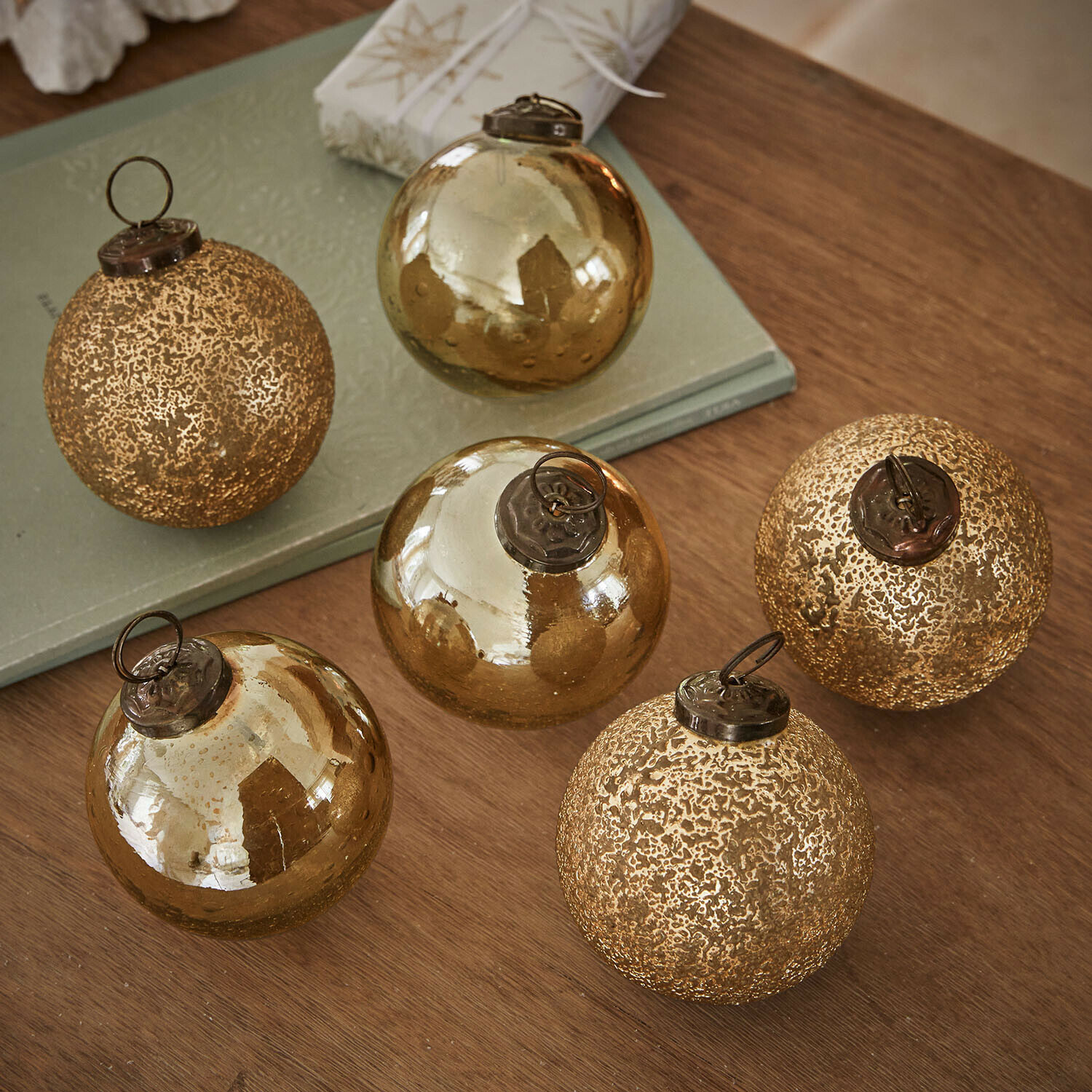 Kerstbal set van 6 Fioravino Set van zes gouden glazen kerstballen met verschillende texturen op een houten tafel